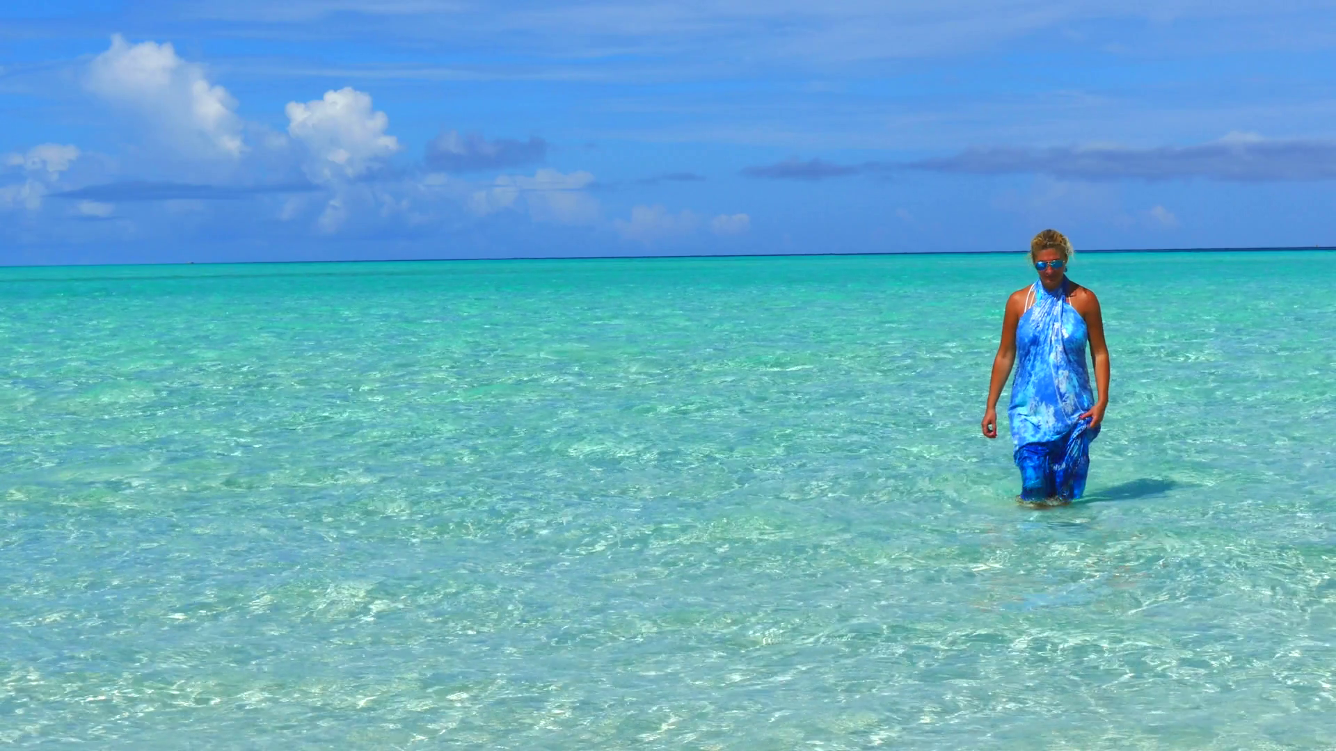 Blonde woman walking out of the crystal clear ocean water.Copy space ...