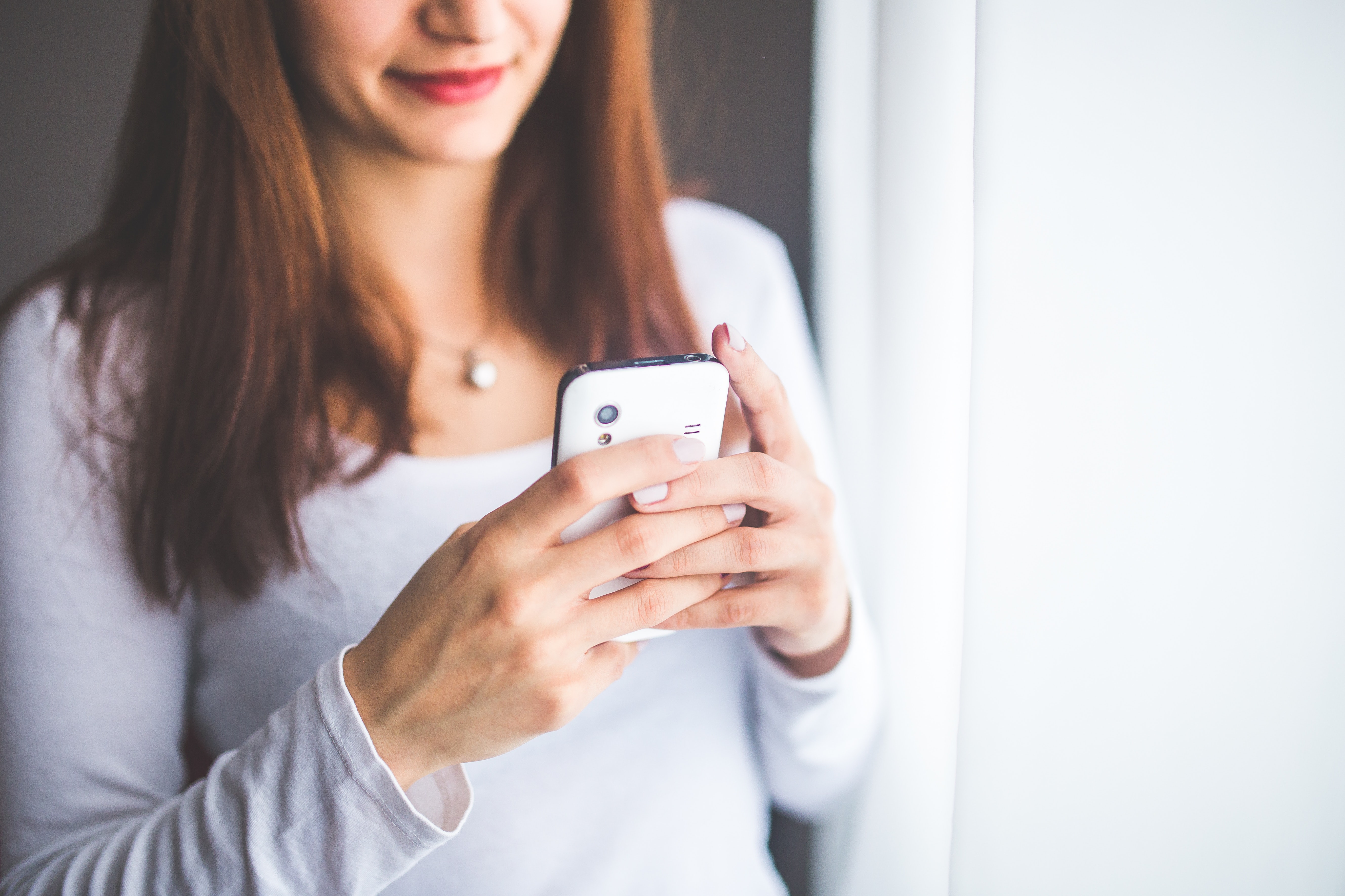 Close up portrait of a young woman typing a text message on mobile phone photo