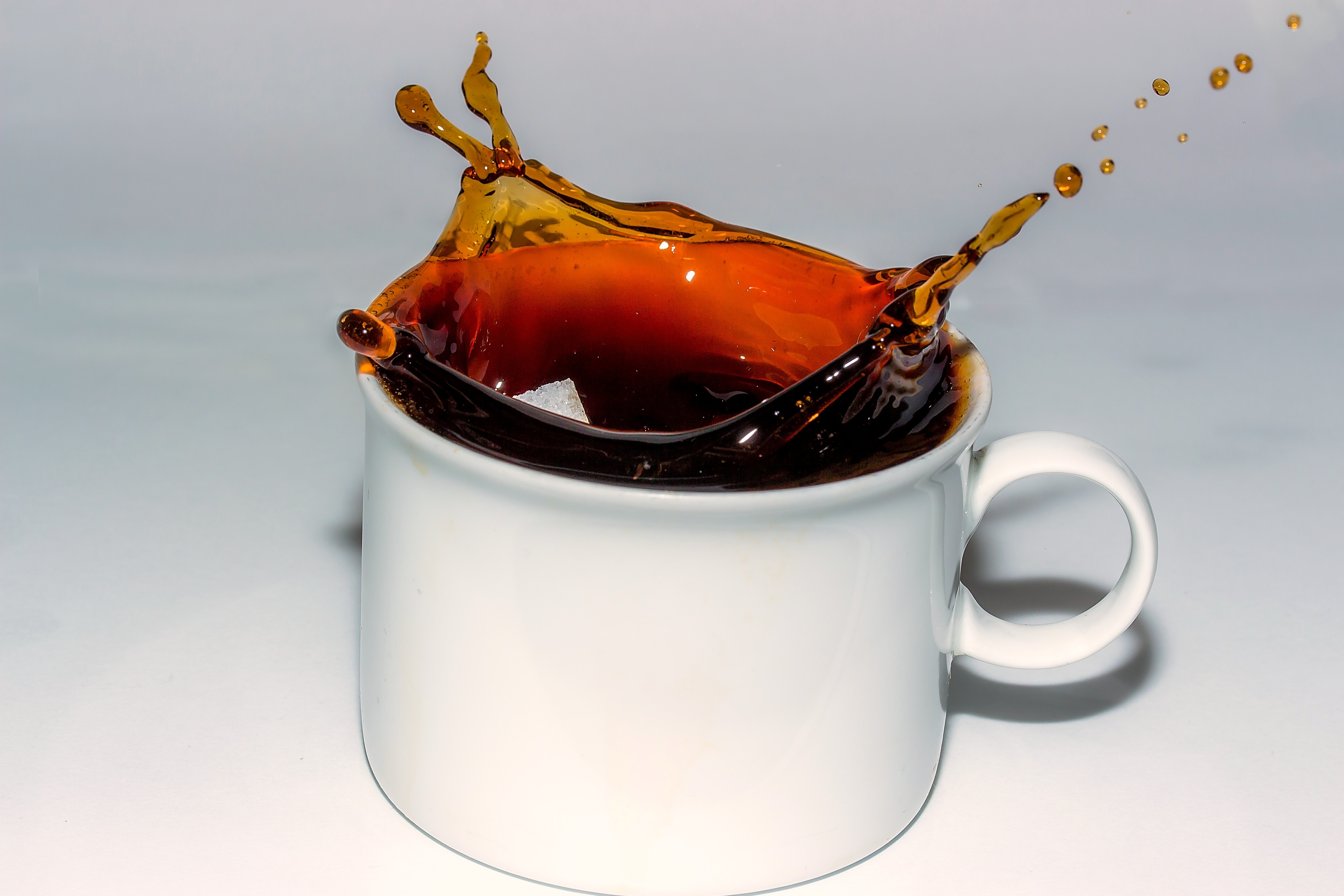 Coffee splashing in cup against white background photo