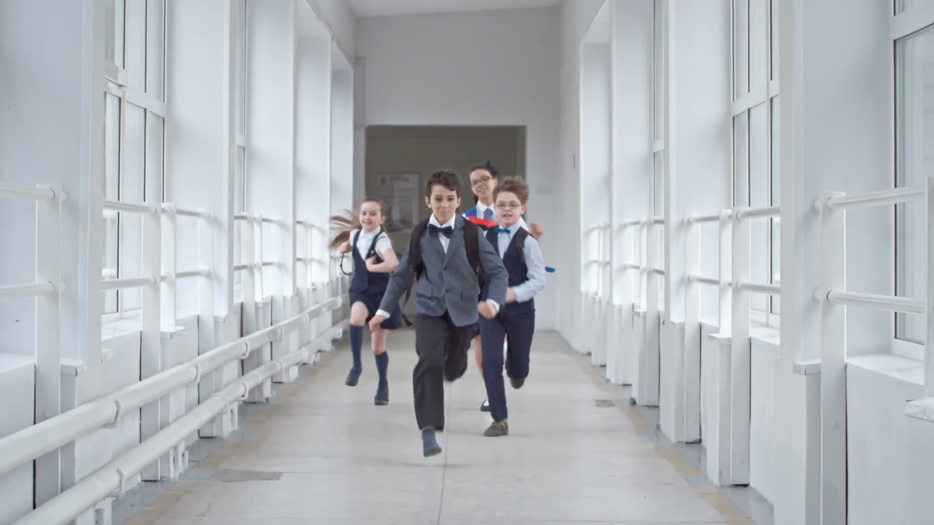Four schoolchildren in uniform running towards the camera through ...