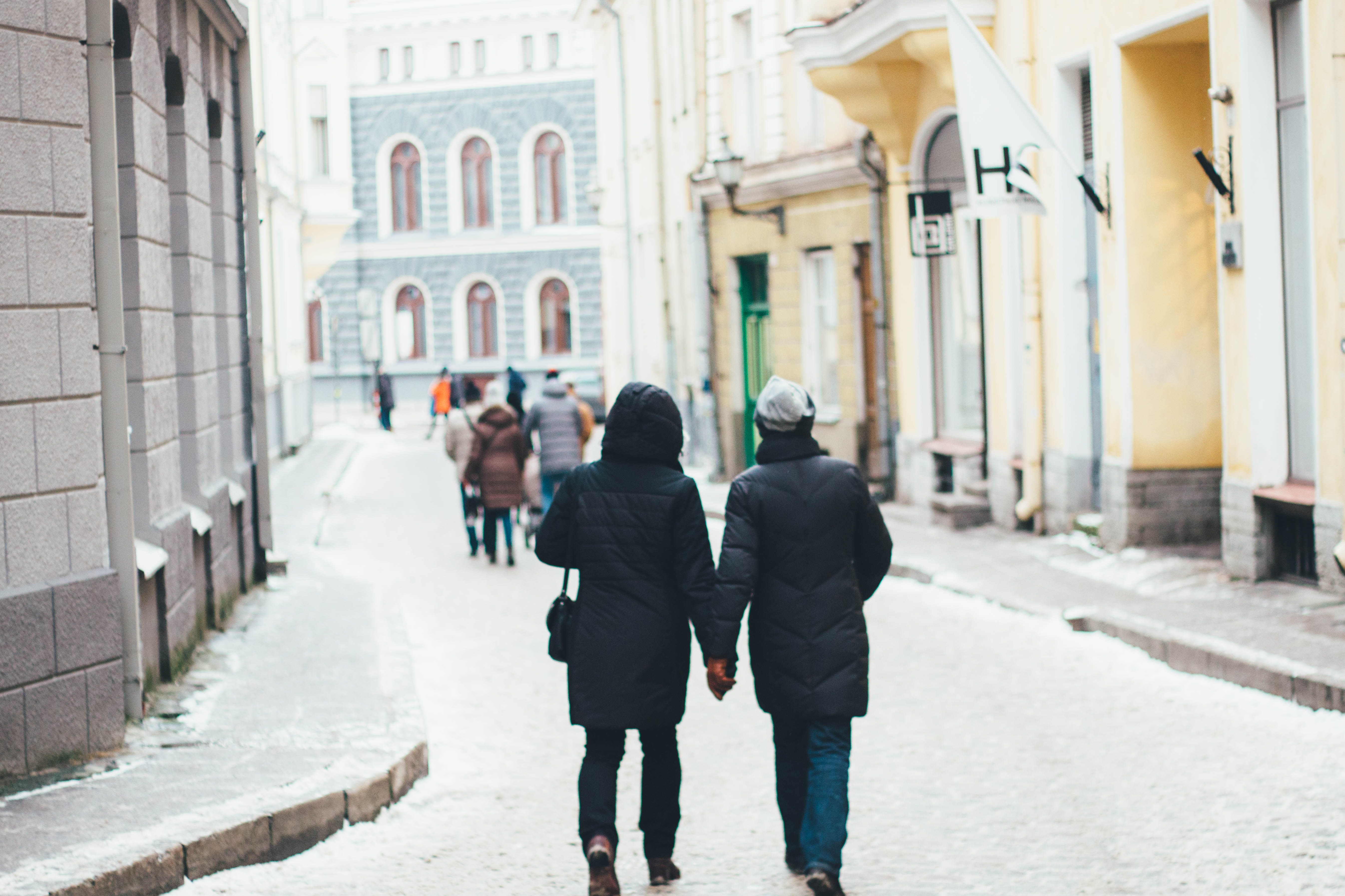 Holding Hand Couple Walking in Street Between Building