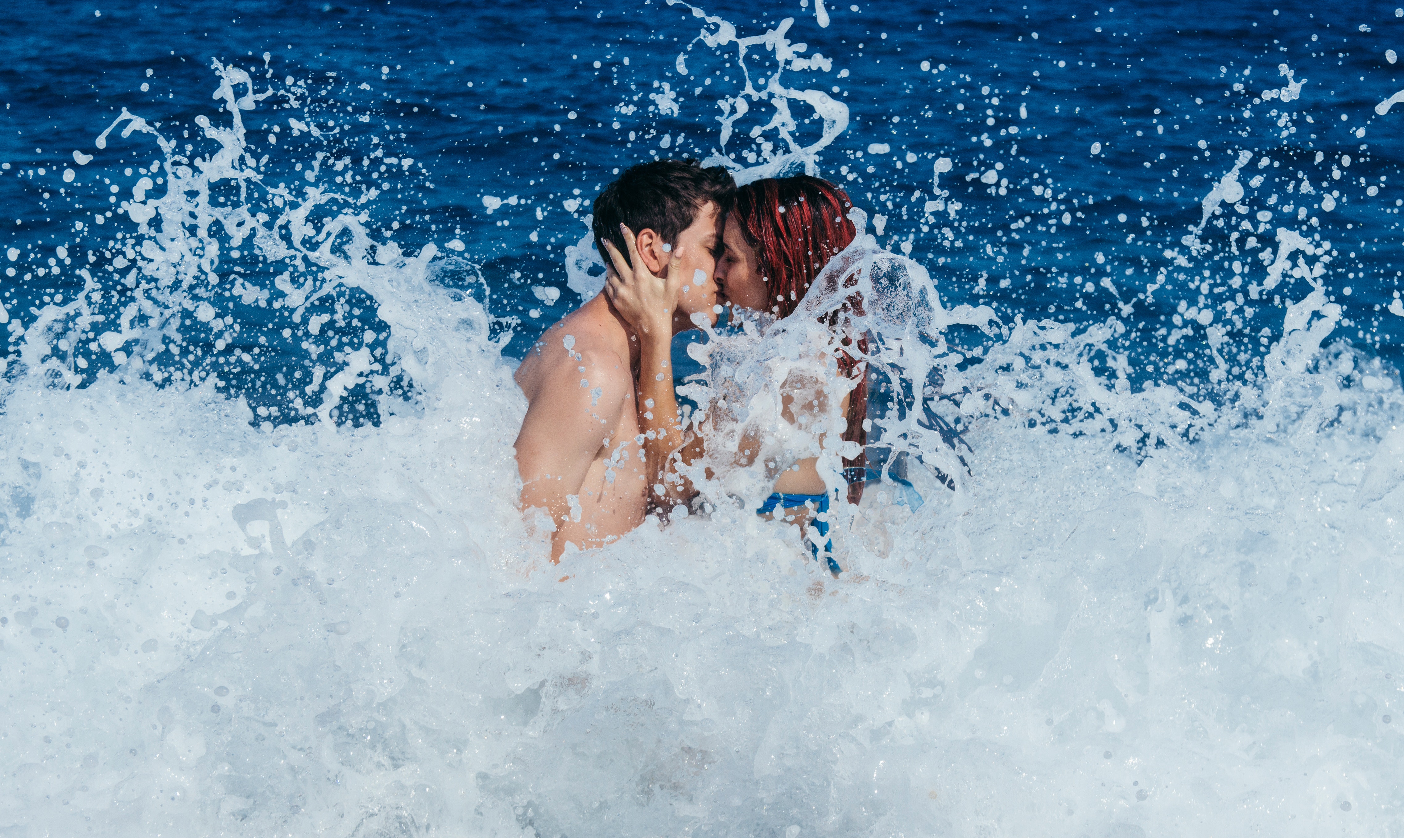 Couple kissing while waves crash photo