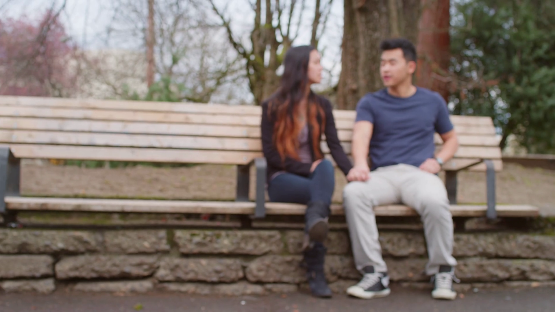 A young couple holding hands and talking on a park bench Stock Video ...