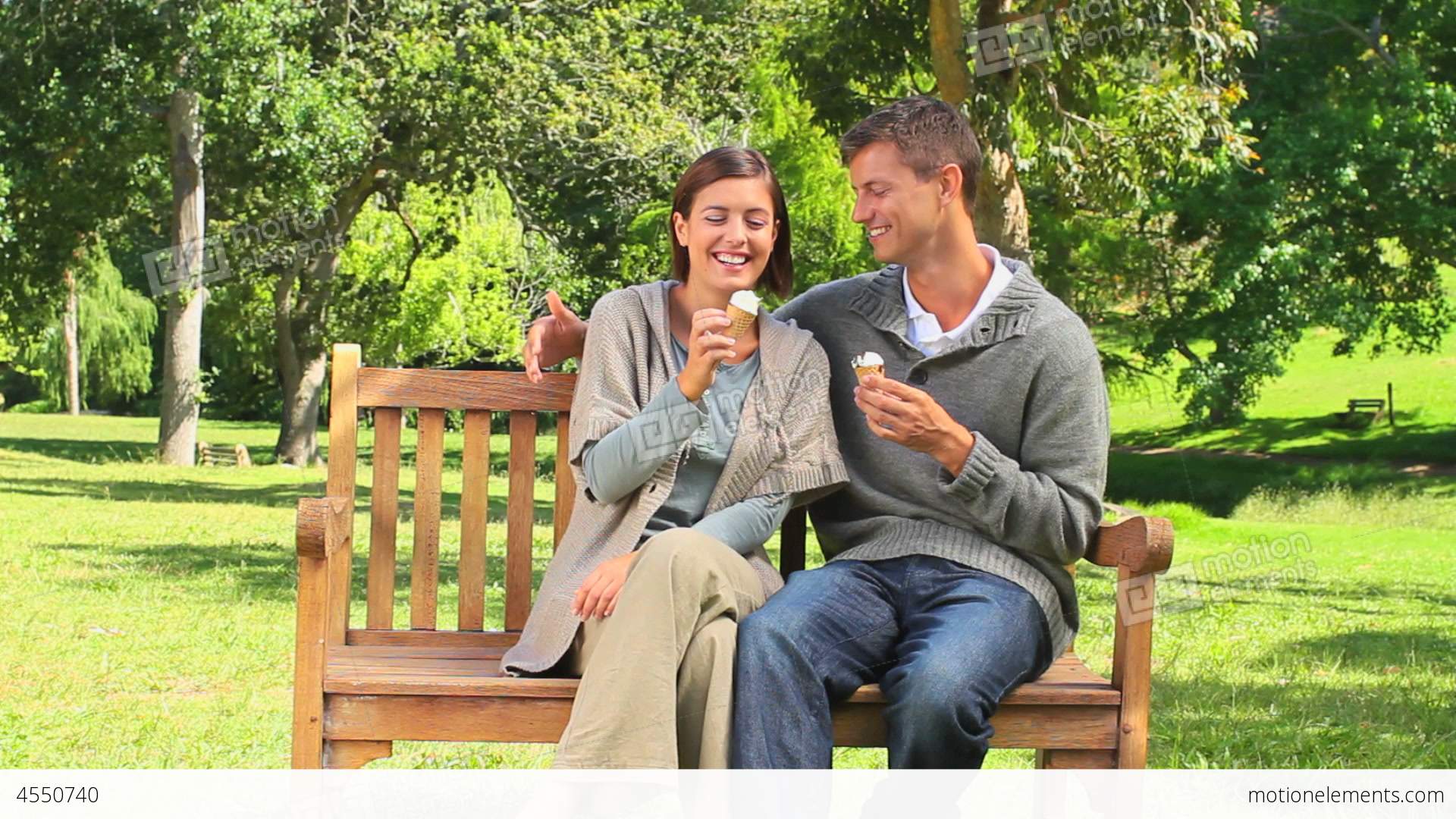 Young Couple Eating Icecream On A Park Bench Stock video footage ...