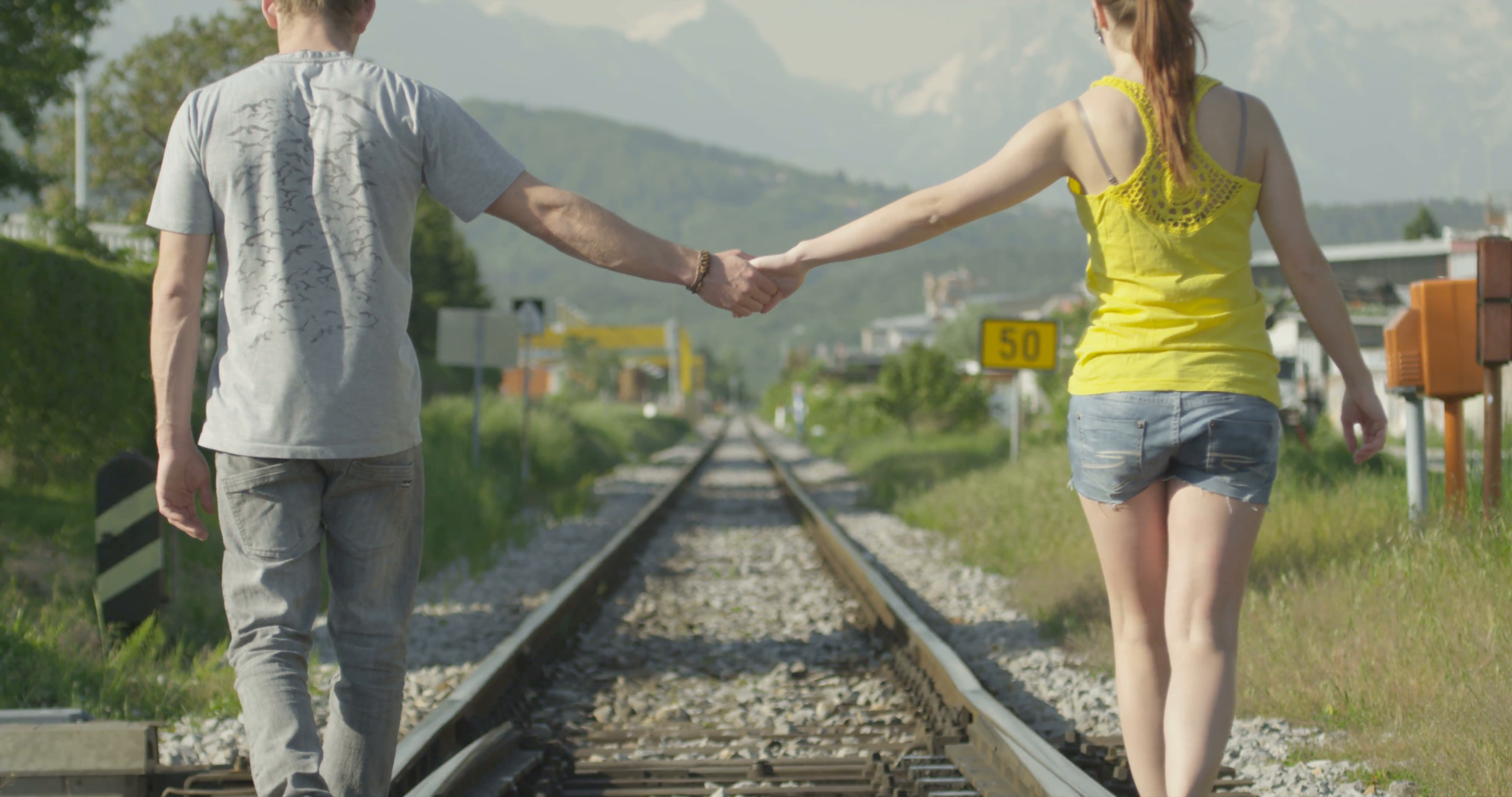 SLOW MOTION: Couple holding hands while walking on railroad tracks ...