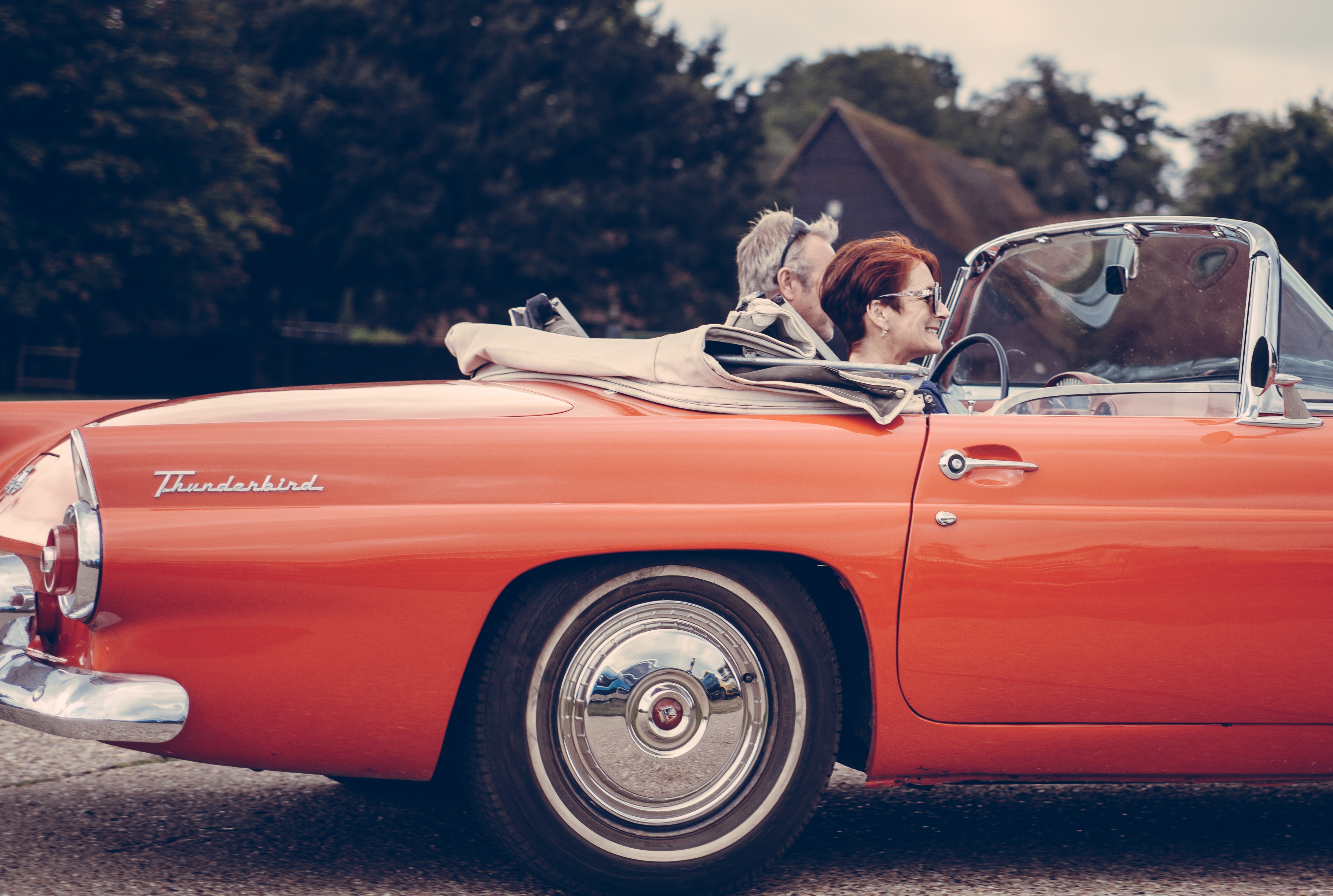 Couple riding red ford thunderbird during daytime photo