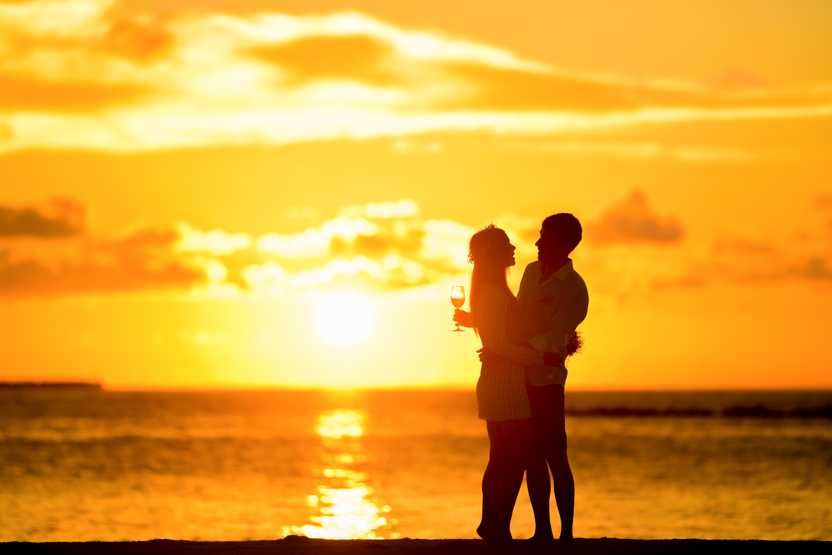 Couple standing in the seashore hugging each other during sunset photo