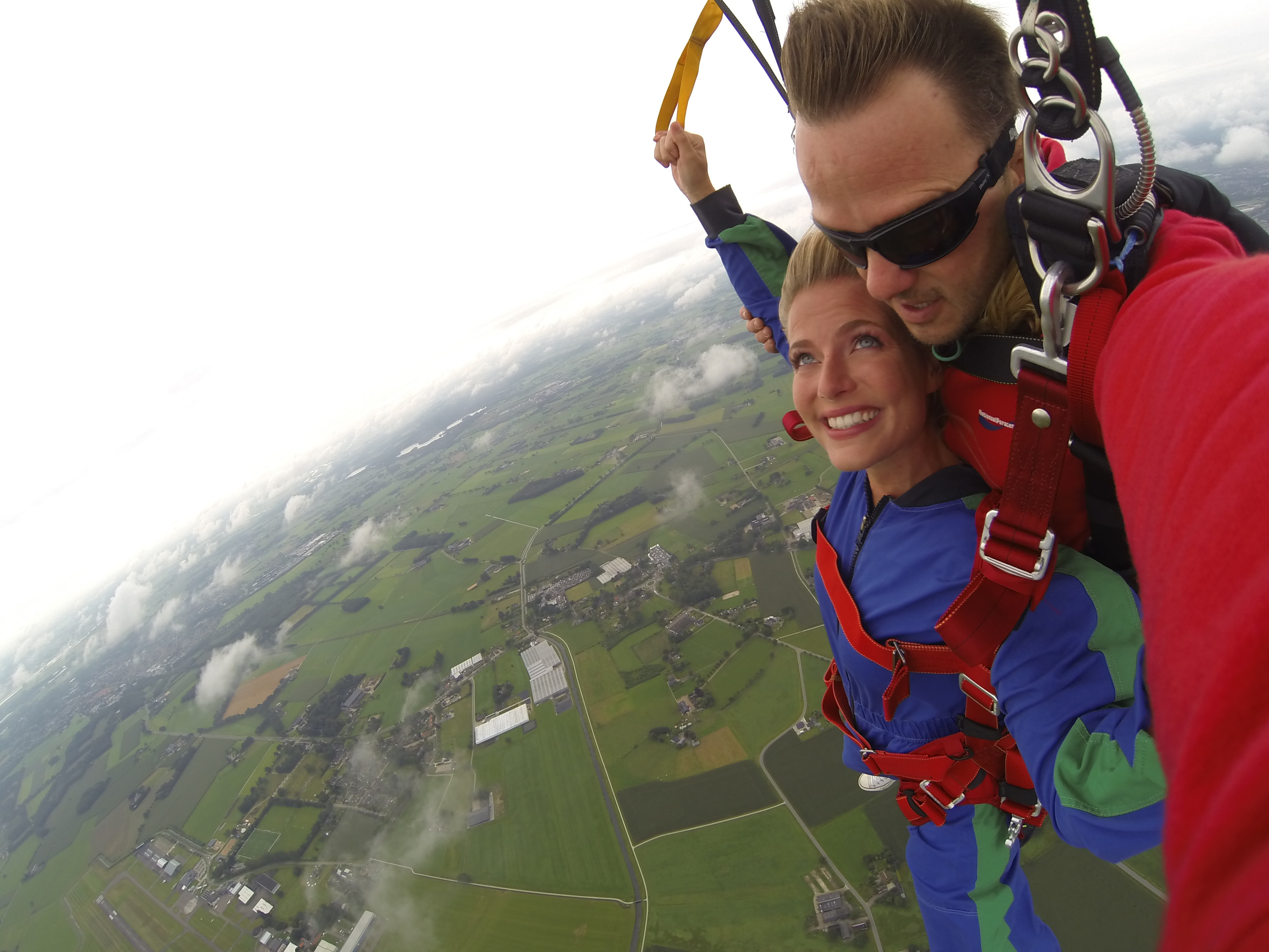 Couple wears red and blue long-sleeved overalls and body harness with parachute on mid-air photo