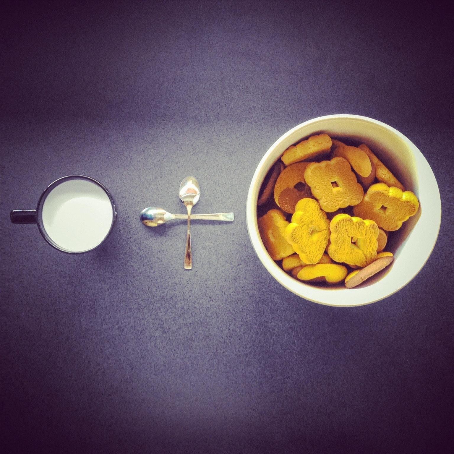 Crackers in round white ceramic cup near two stainless steel spoons and black ceramic mug photo
