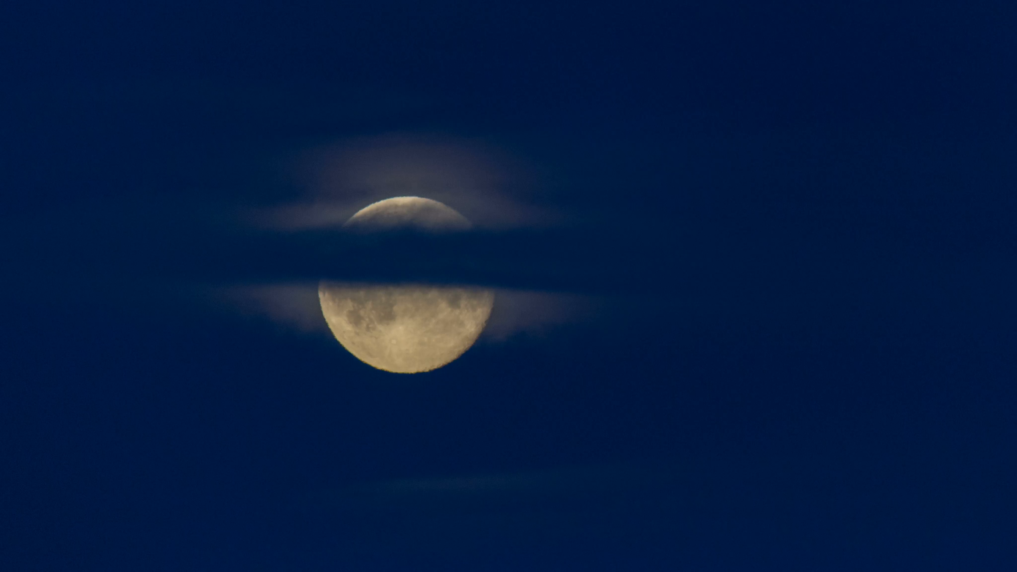 brilliant large full moon rising through wispy clouds on dark blue ...