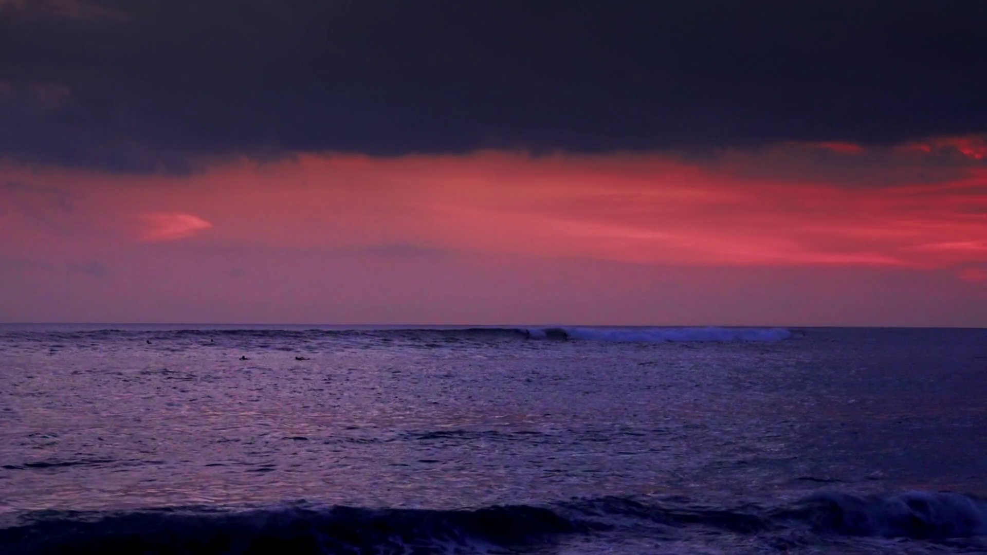 Dark night sky and rolling ocean waves breaking on shore in twilight ...