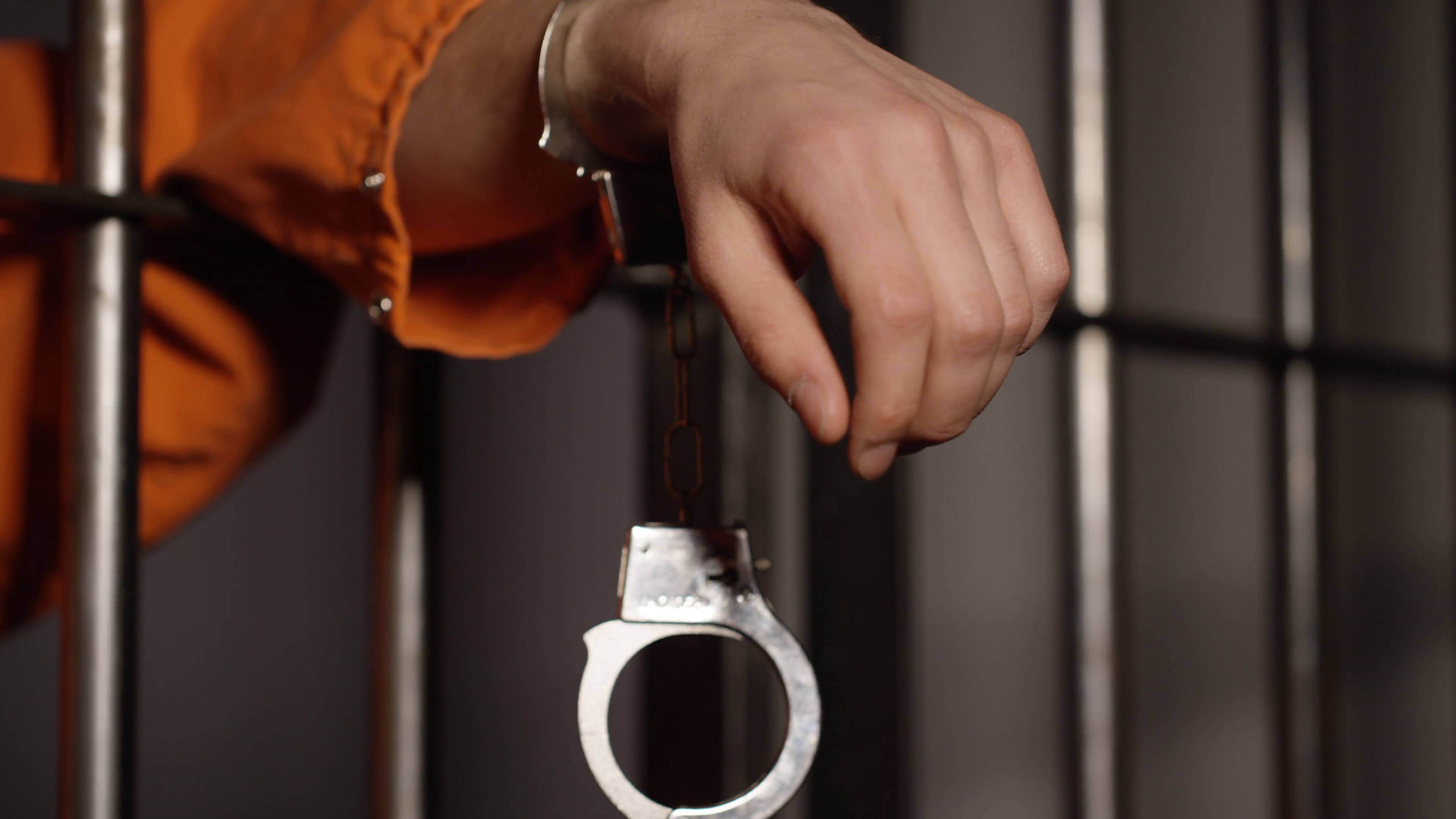 Prison cells in Jail - Handcuff dangling from man's arm in cell ...