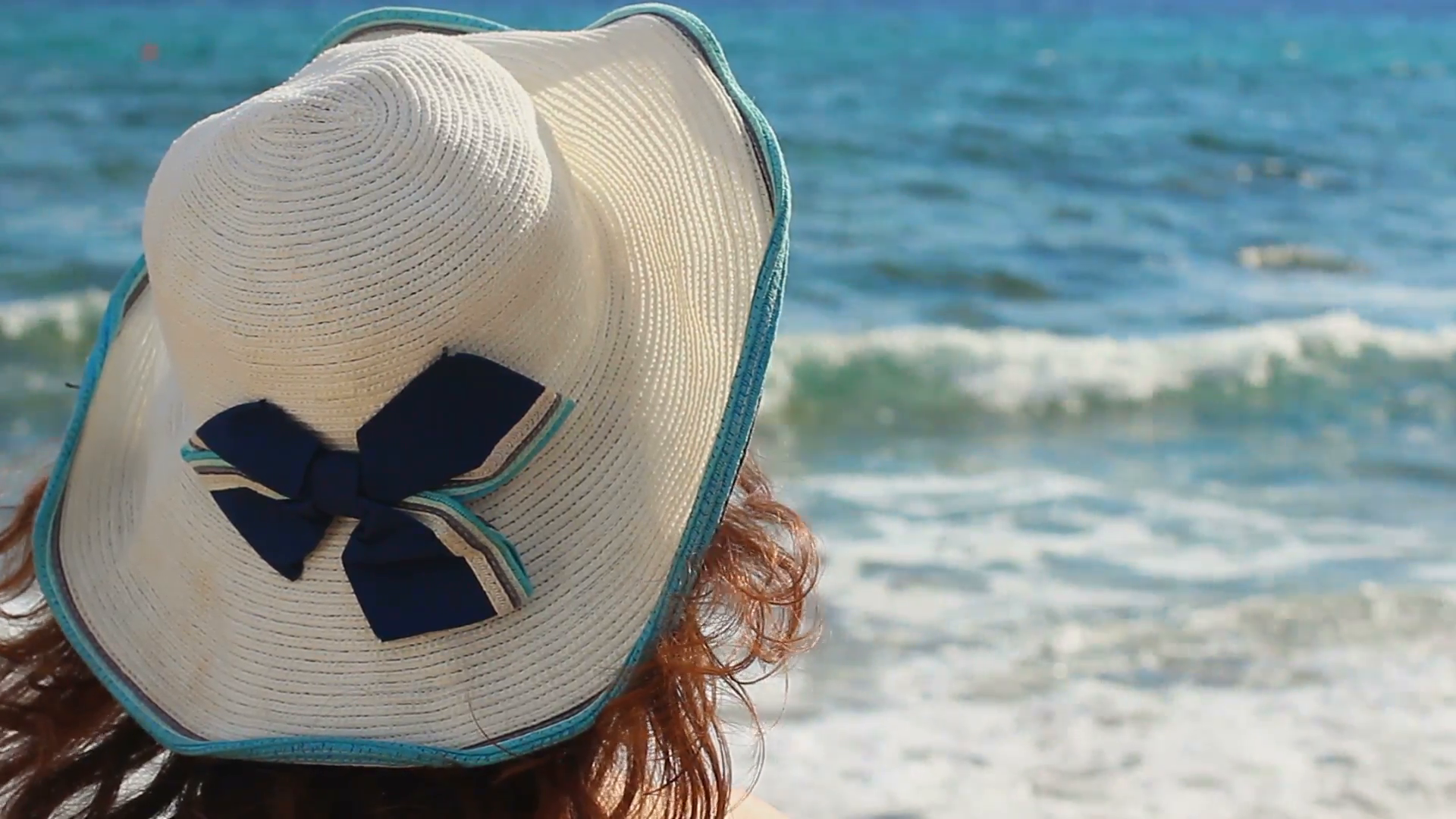 Closeup of brunette female in hat looking at sea waves, enjoying ...