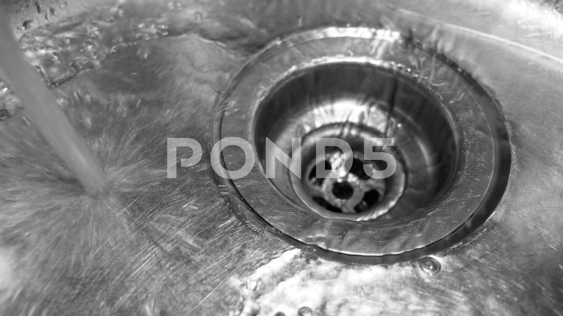 Slow motion kitchen sink. Closeup of water stream going down drain ...
