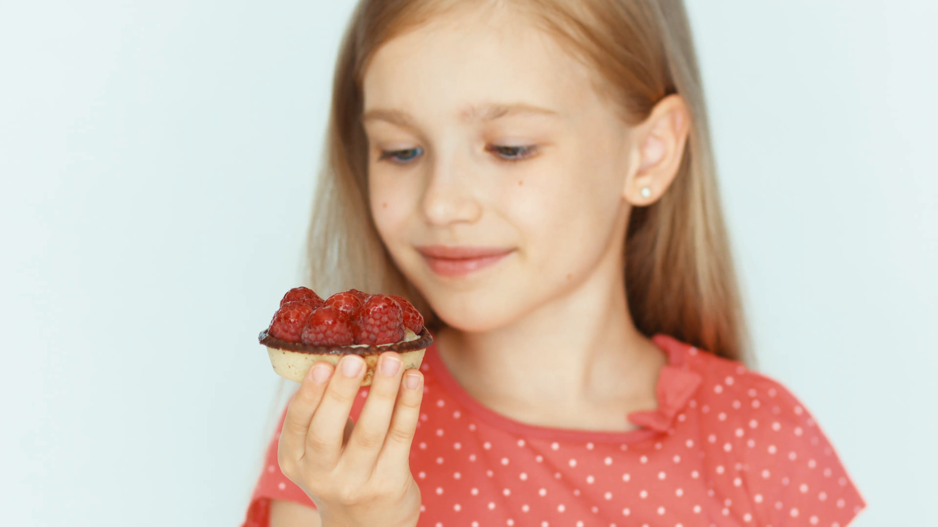 Girl holding and sniffing a cake with raspberries. Closeup Stock ...