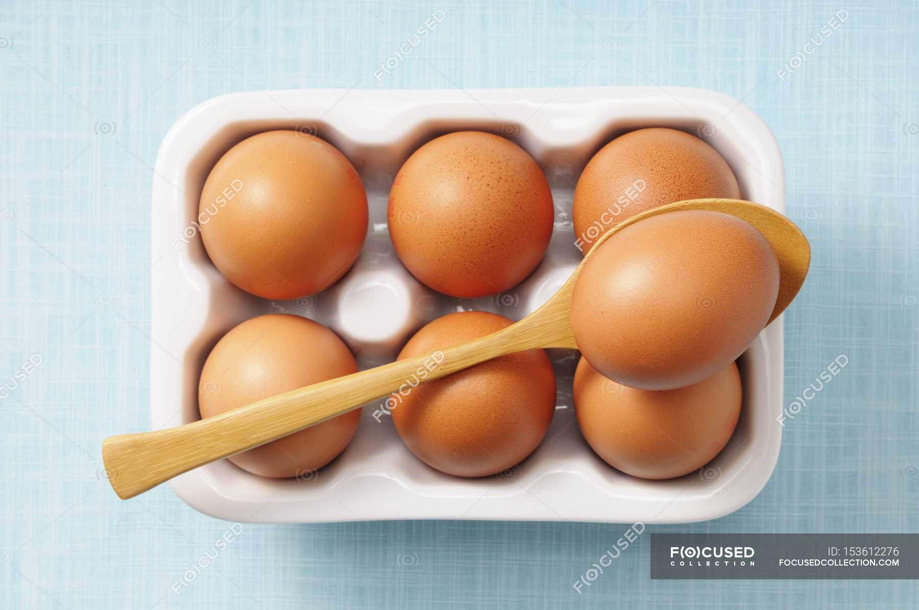 Brown eggs in box with wooden spoon — Stock Photo | #153612276