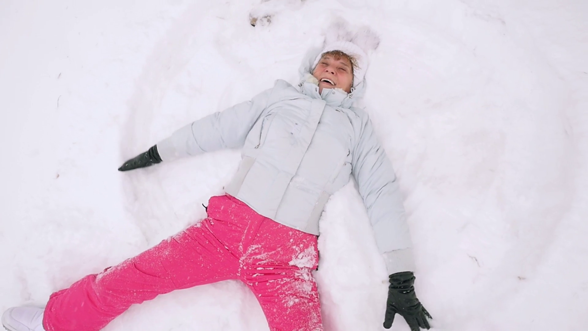Happy mature woman in winter wear lying in snowdrift enjoying ...