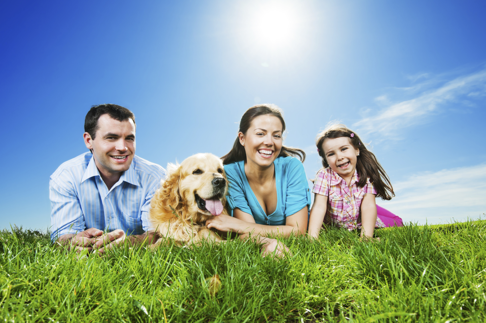 Happy family lying in the park with their dog. - FloraTummys
