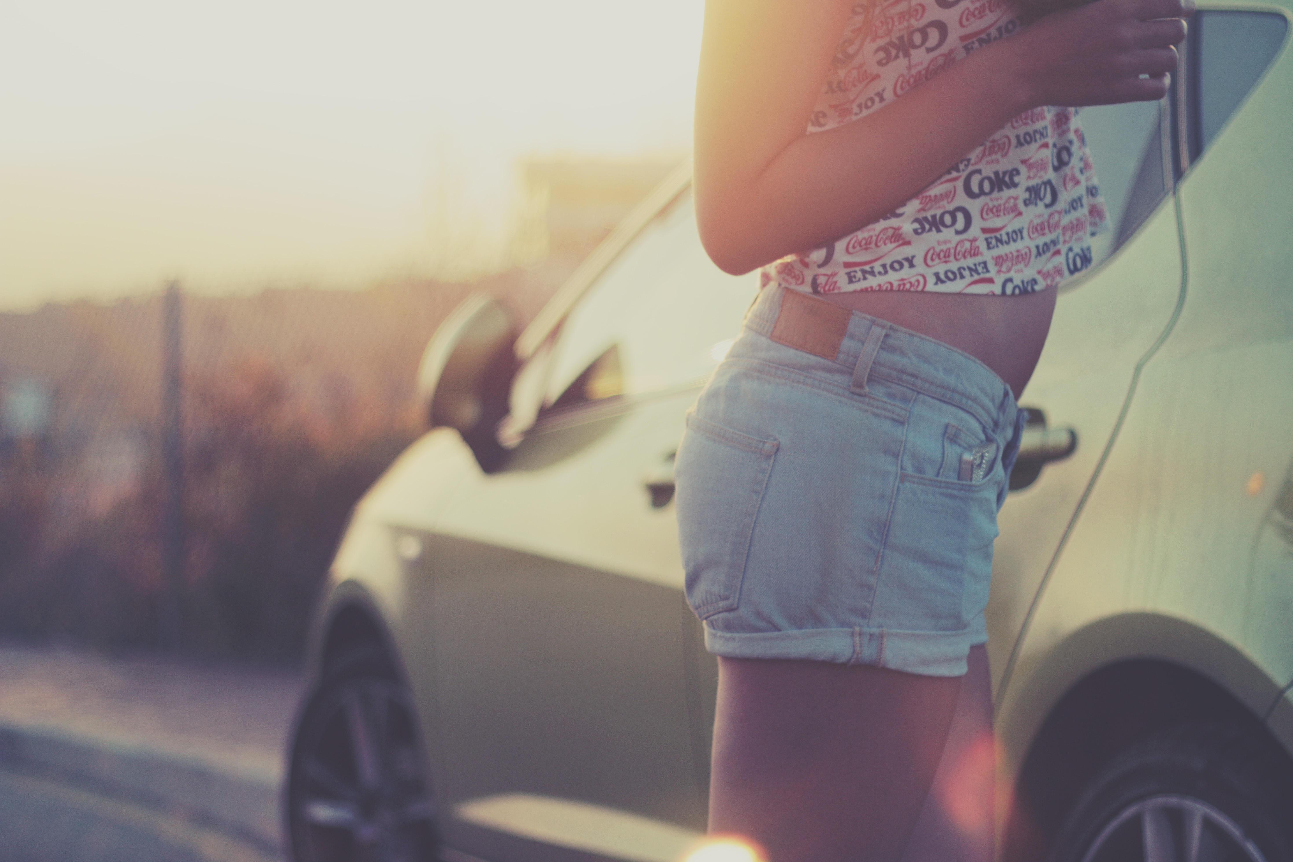 Female in coke shirt and jean shorts by car photo