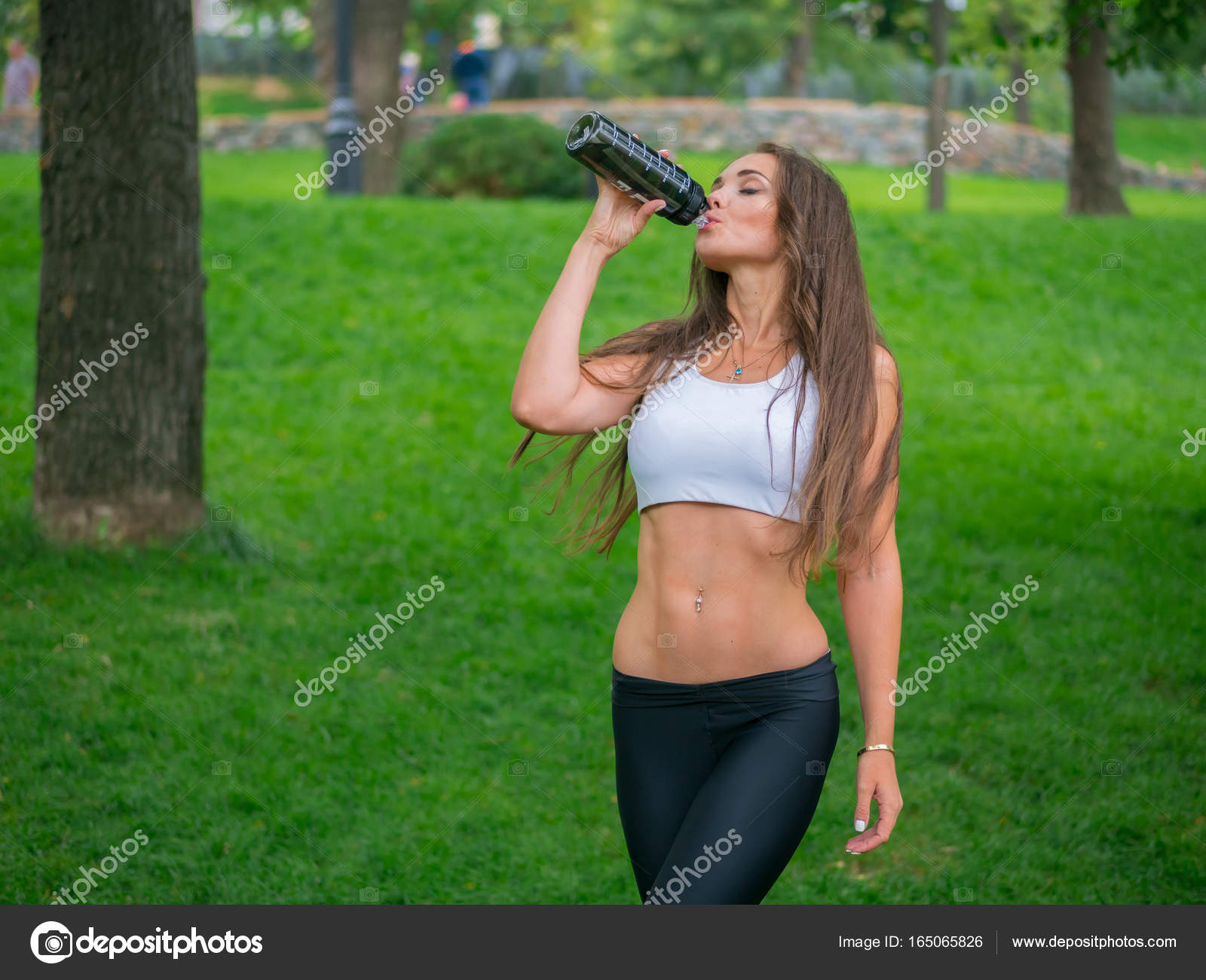 Thirsty female jogger drinking fresh water after training. Young ...