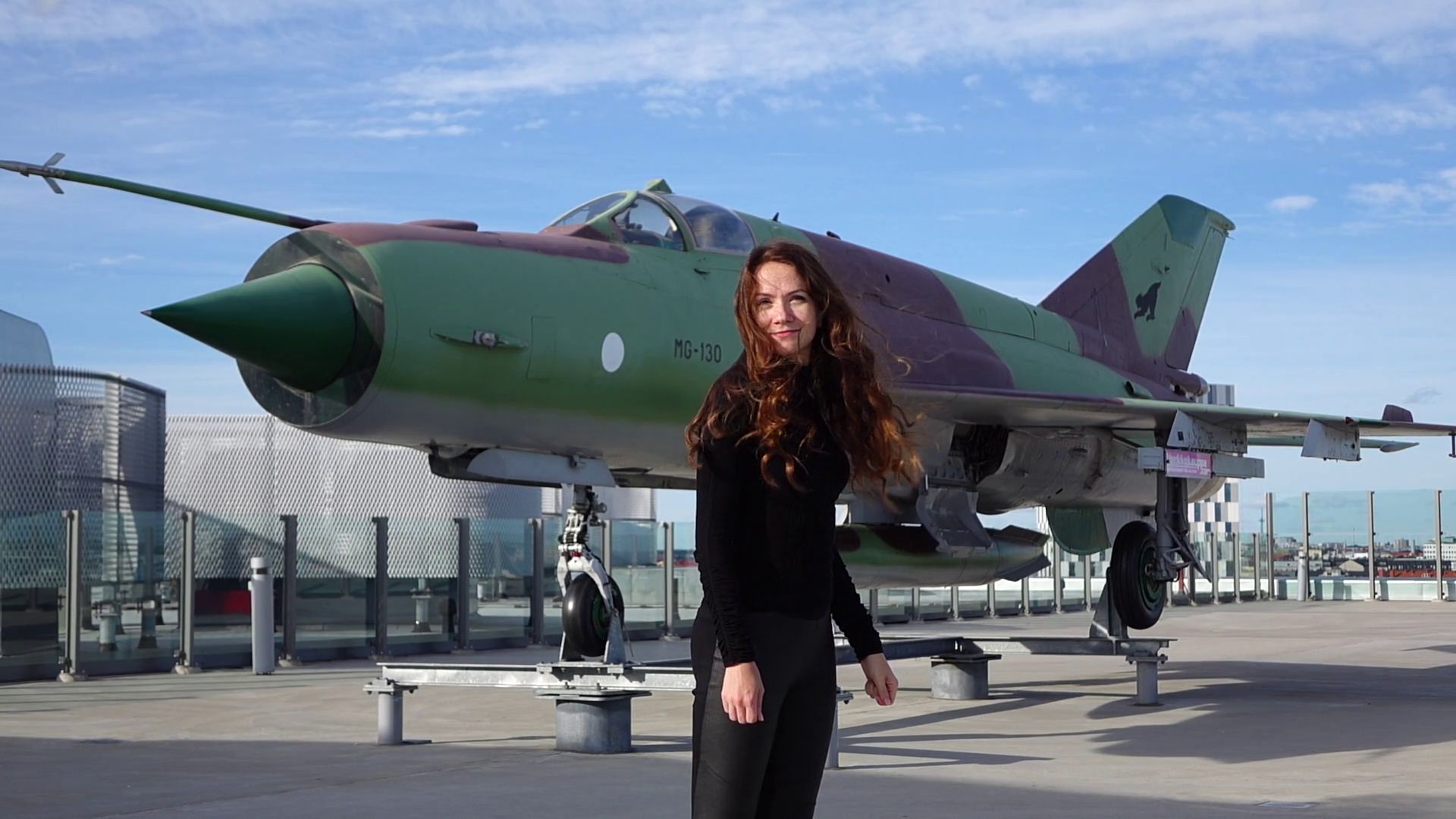 Woman stand against military plane monument, long hair wave on wind ...