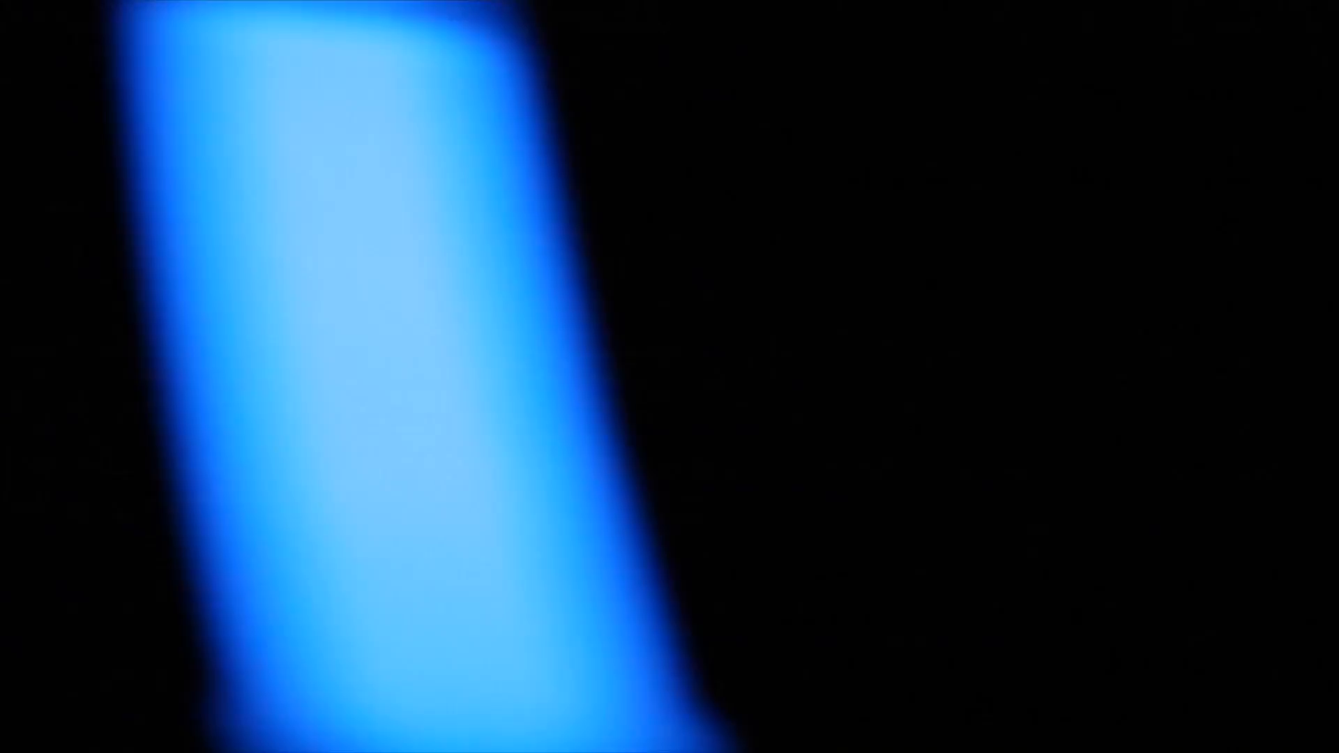 Fluorescent blue light moving from side to side on black background ...