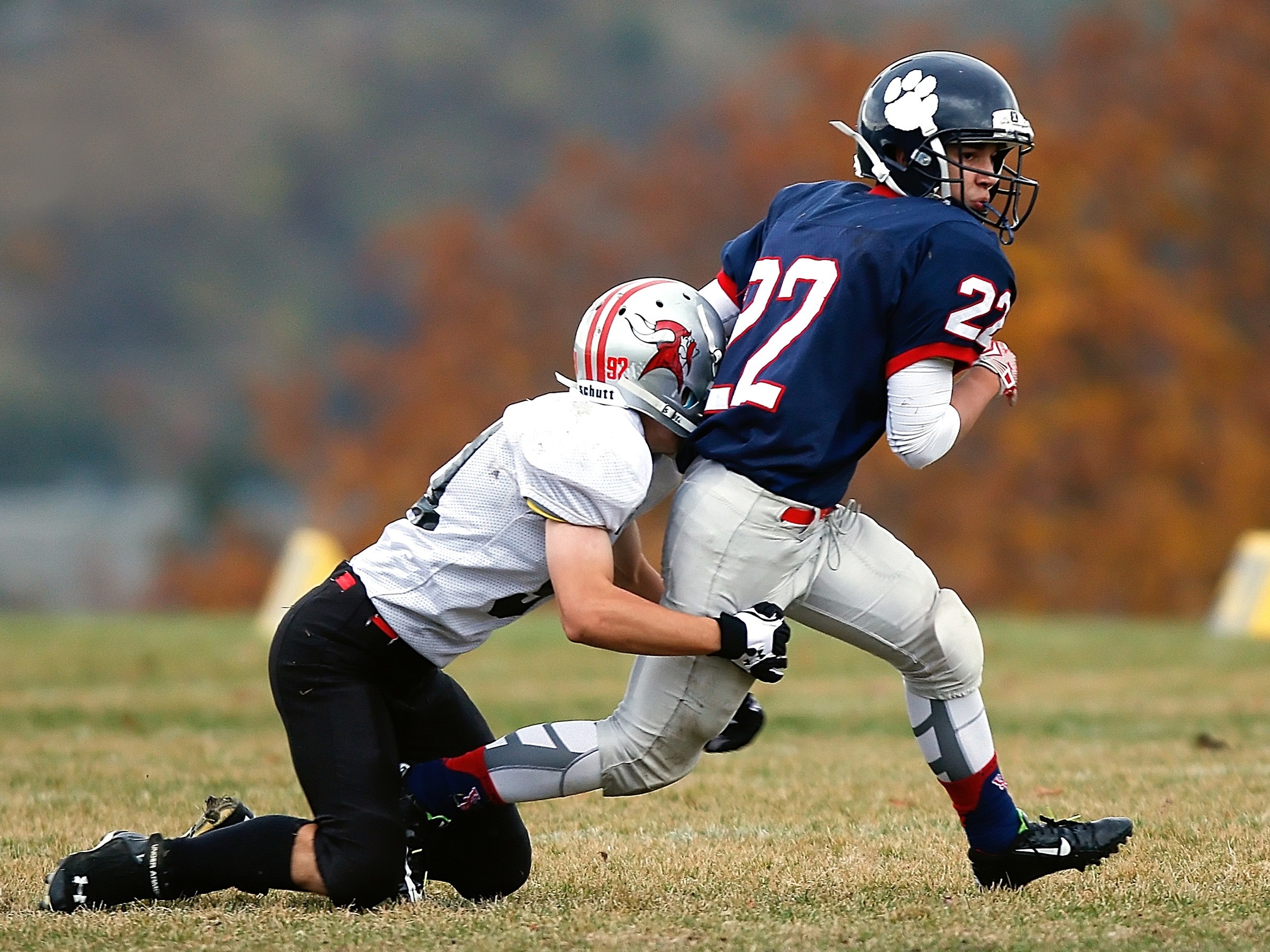 Football player in white trying to stop a player in blue photo