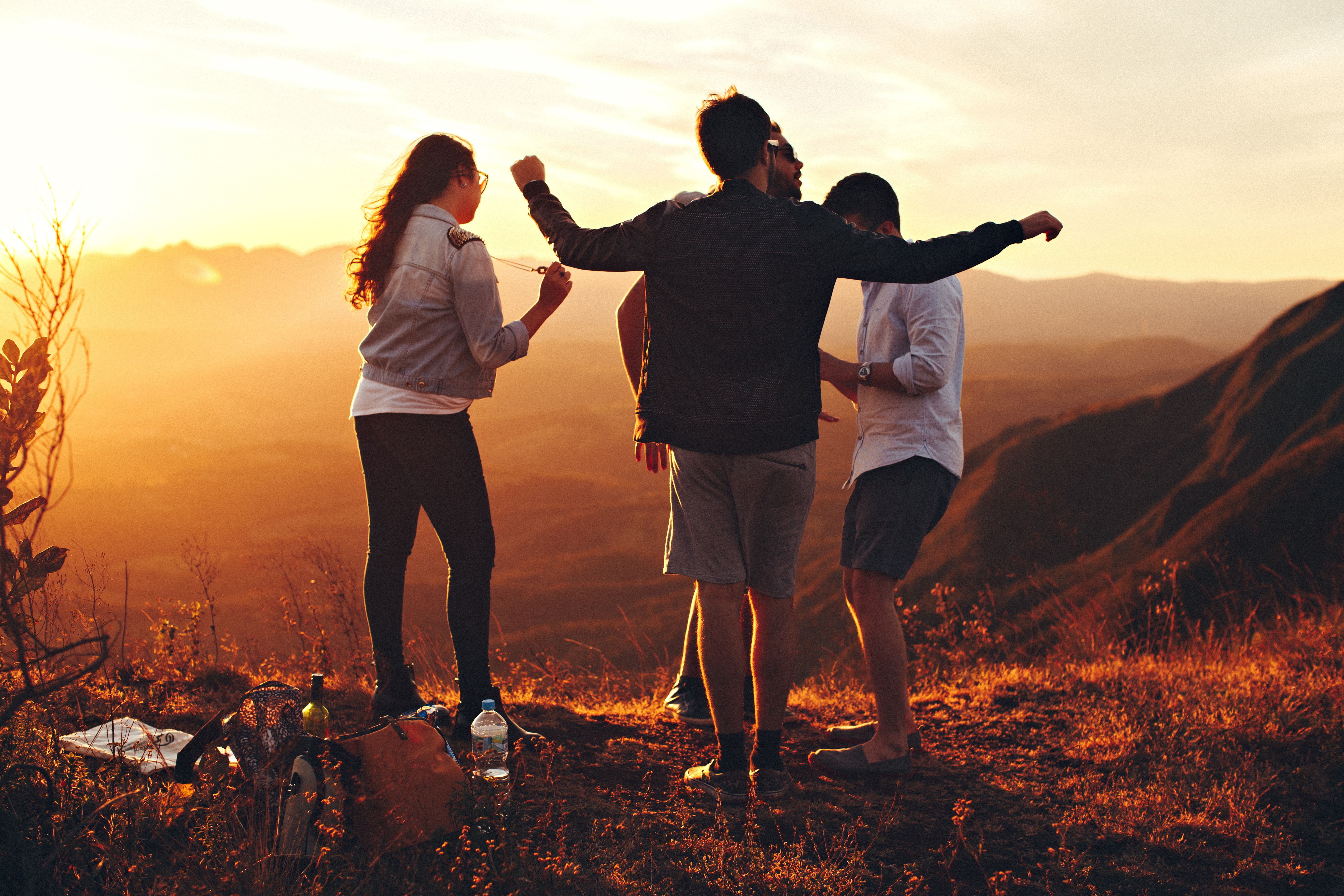 Four person standing at top of grassy mountain photo