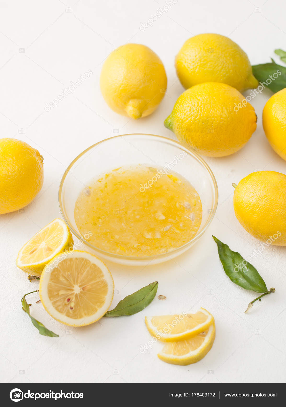 Fresh lemons with leaves and chopped lemons and sugar in a bowl on a ...
