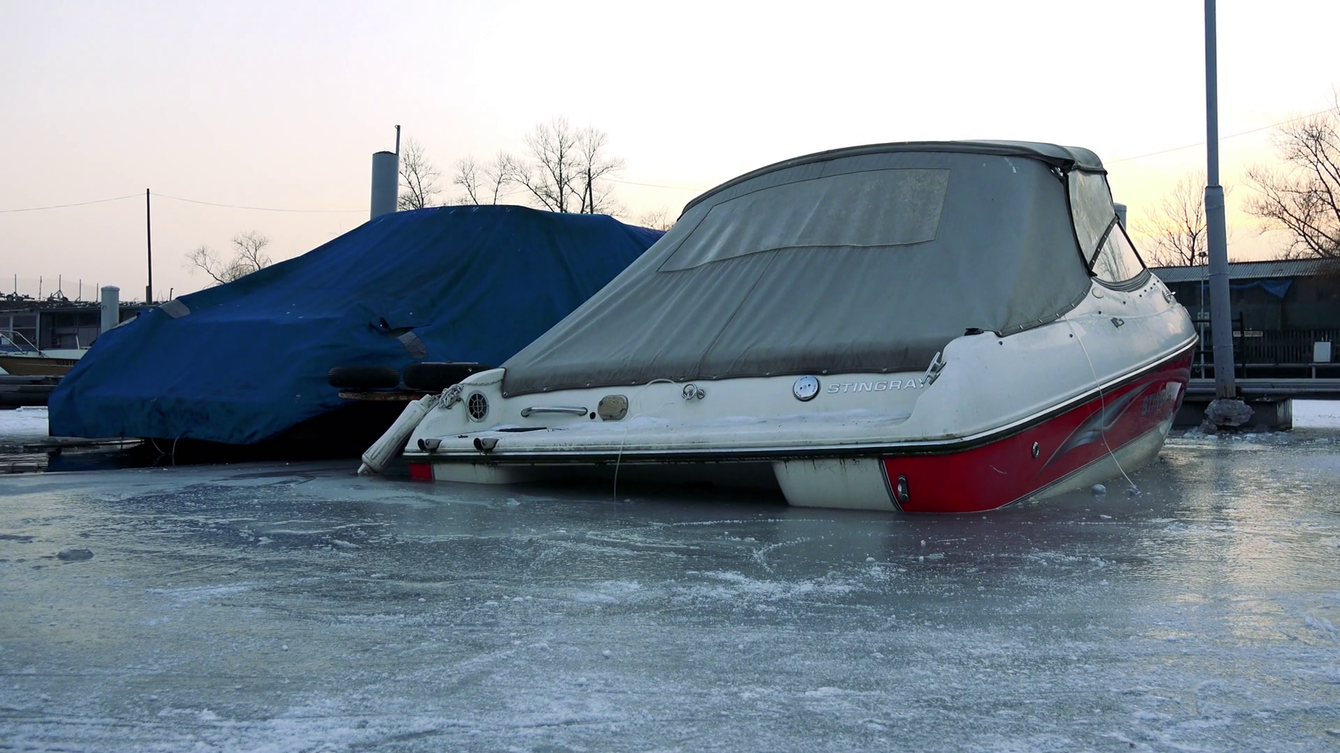 Two boats parked at a wharf on a frozen river in winter and covered ...