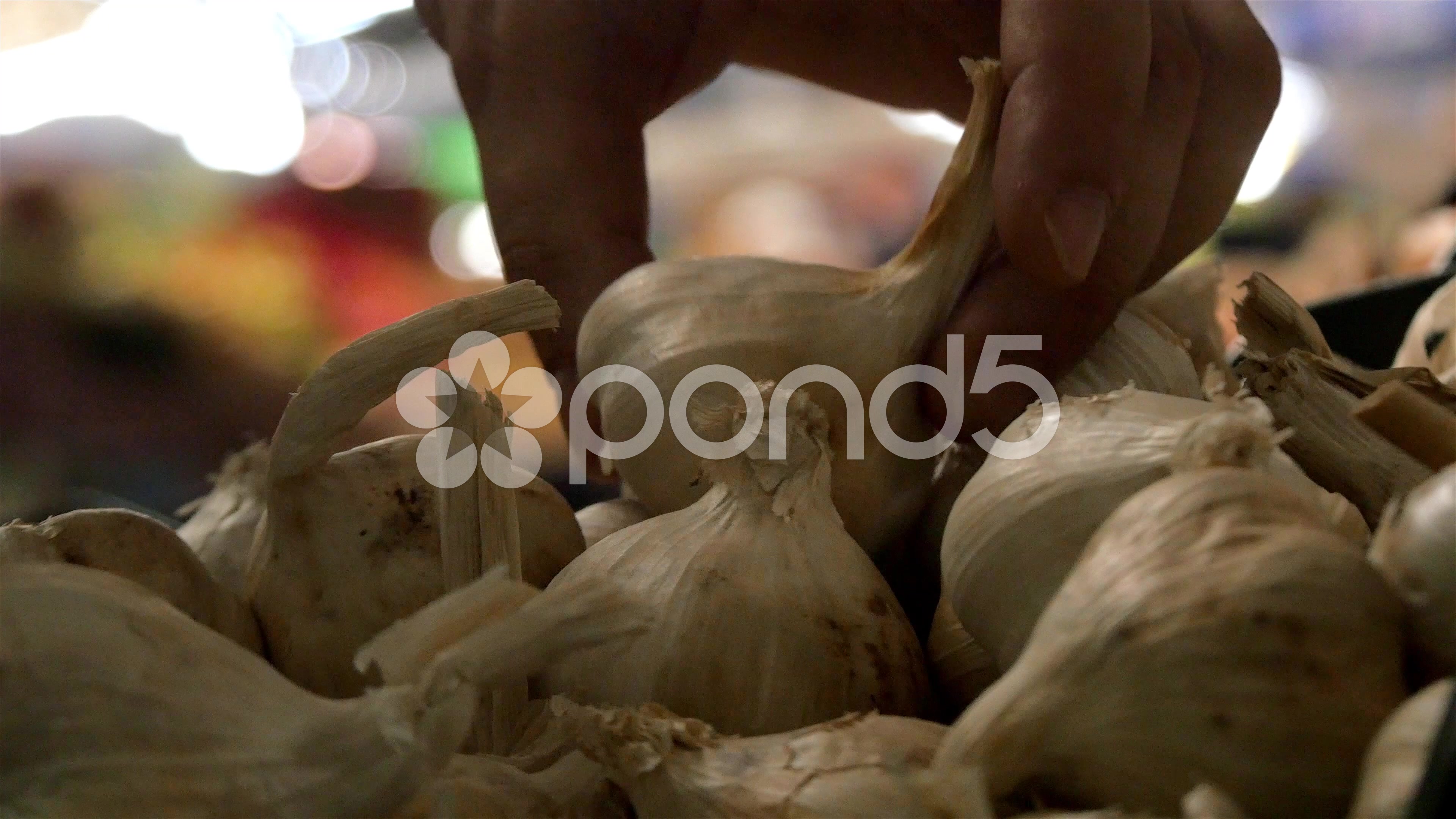 Garlic on stand, customer takes few heads of garlic, close up ...