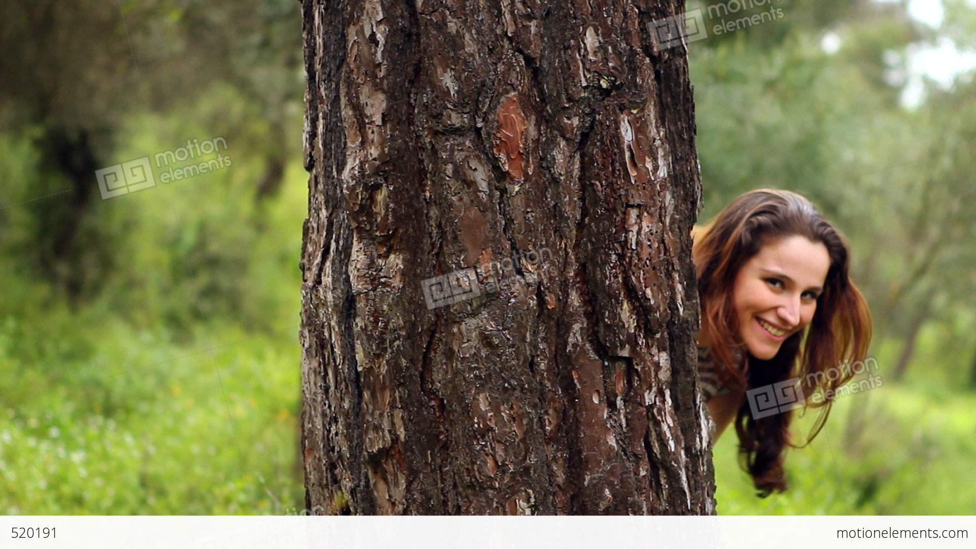Beautiful Girl Looking At The Camera Behind Tree Stock video footage ...