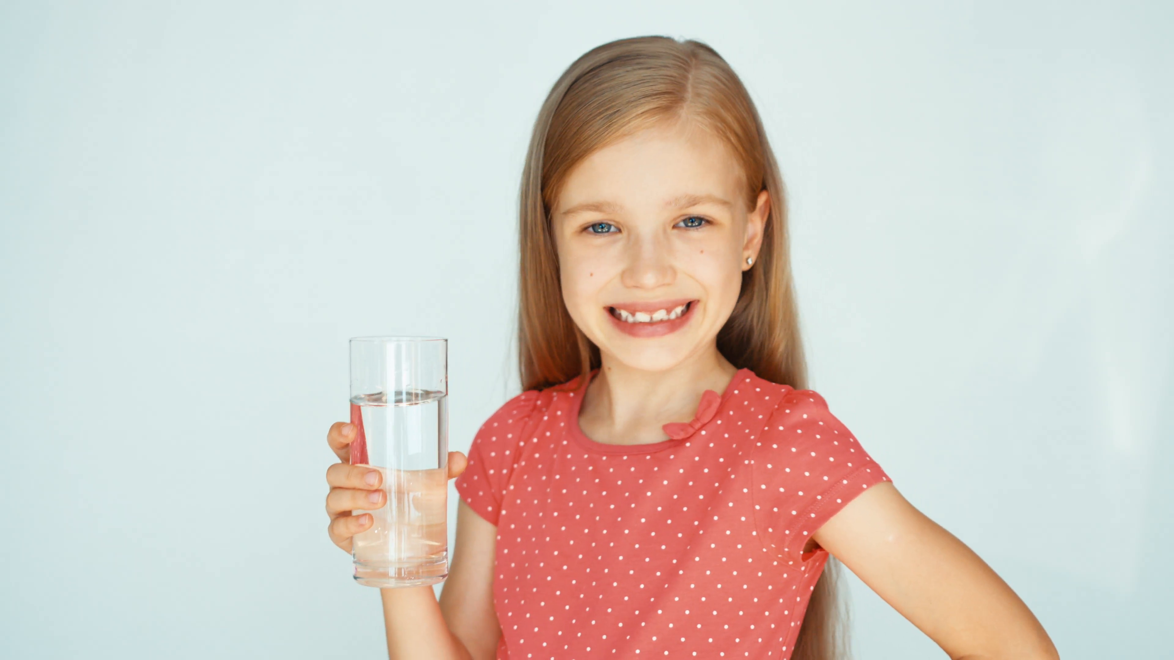 Girl drinking water from glass and smiling at camera. Child on the ...