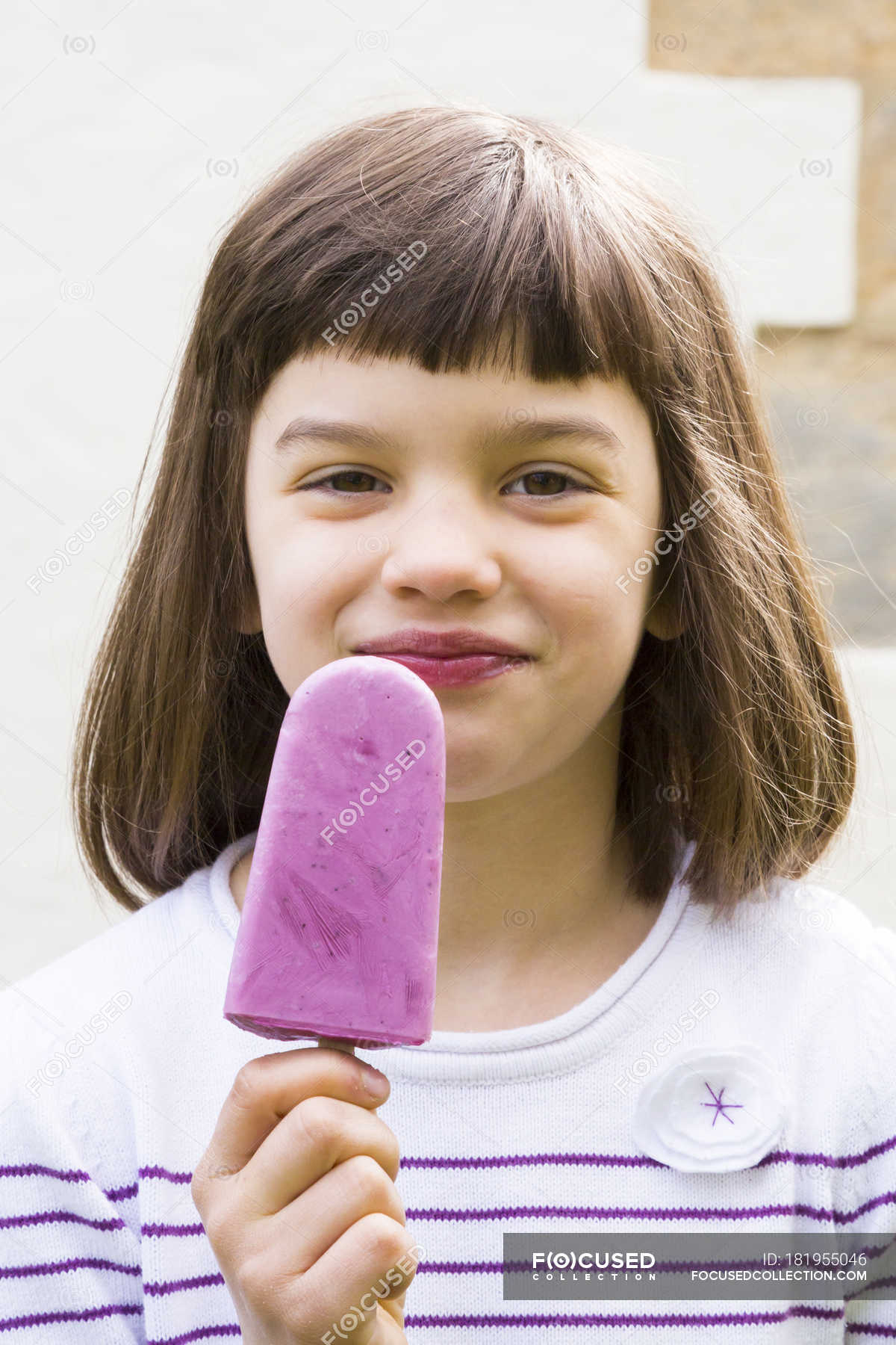 Little girl holding yoghurt blueberry ice lolly and smiling at ...