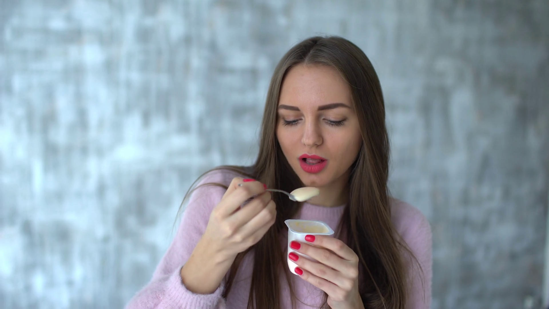Portrait of Beautiful young woman with long hair eating yogurt. 4 k ...