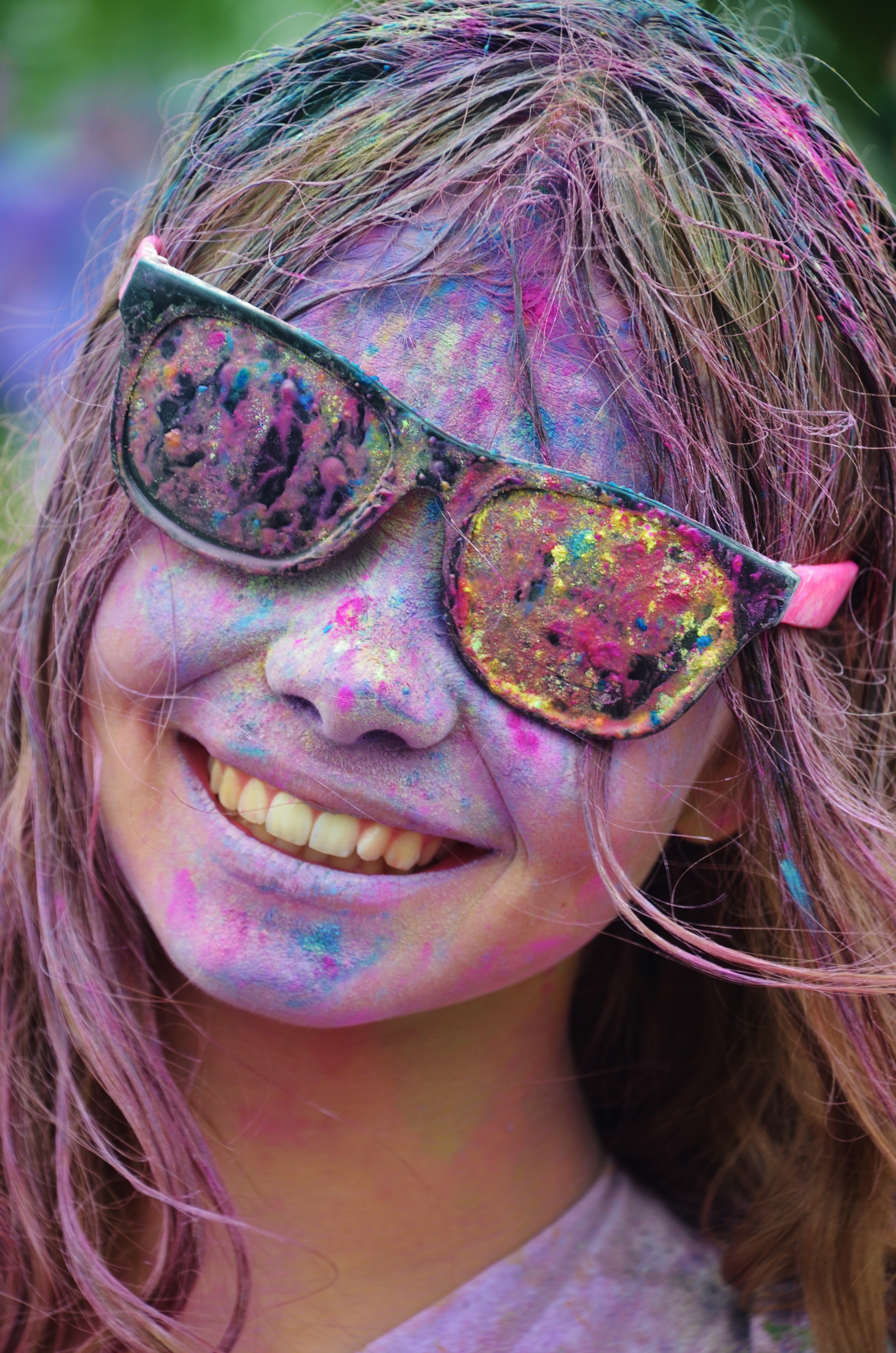 Girl in black framed sunglasses with color on her face from color run smiling photo