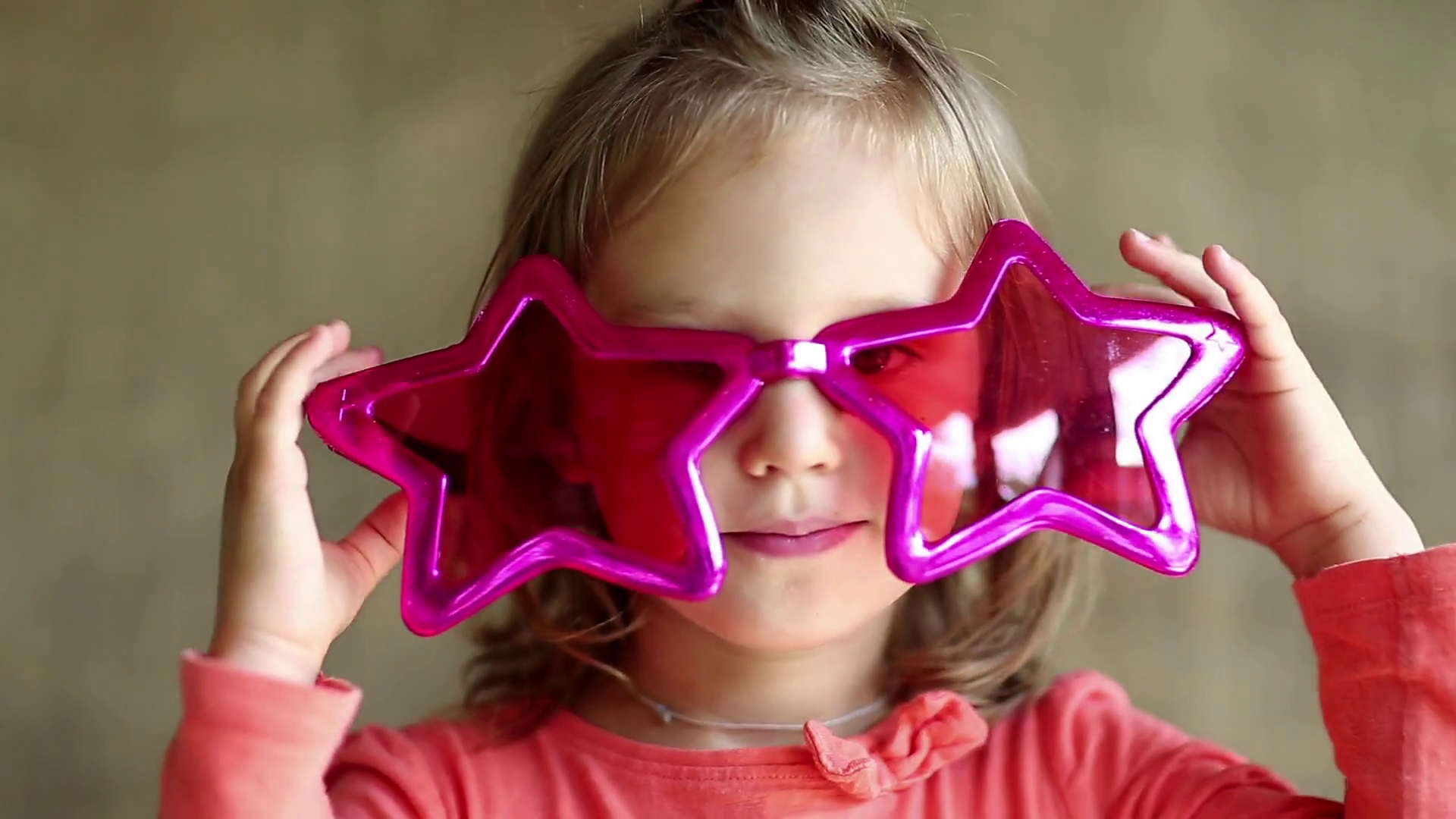 Pretty little girl in big glasses in the shape of stars looks at the ...