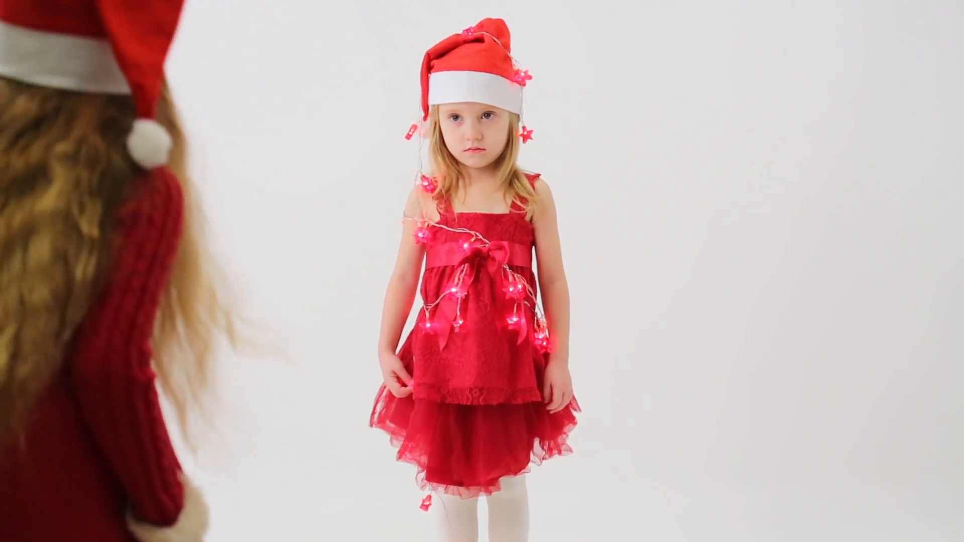 One little girl in a red dress with bell Santa Claus removes a ...