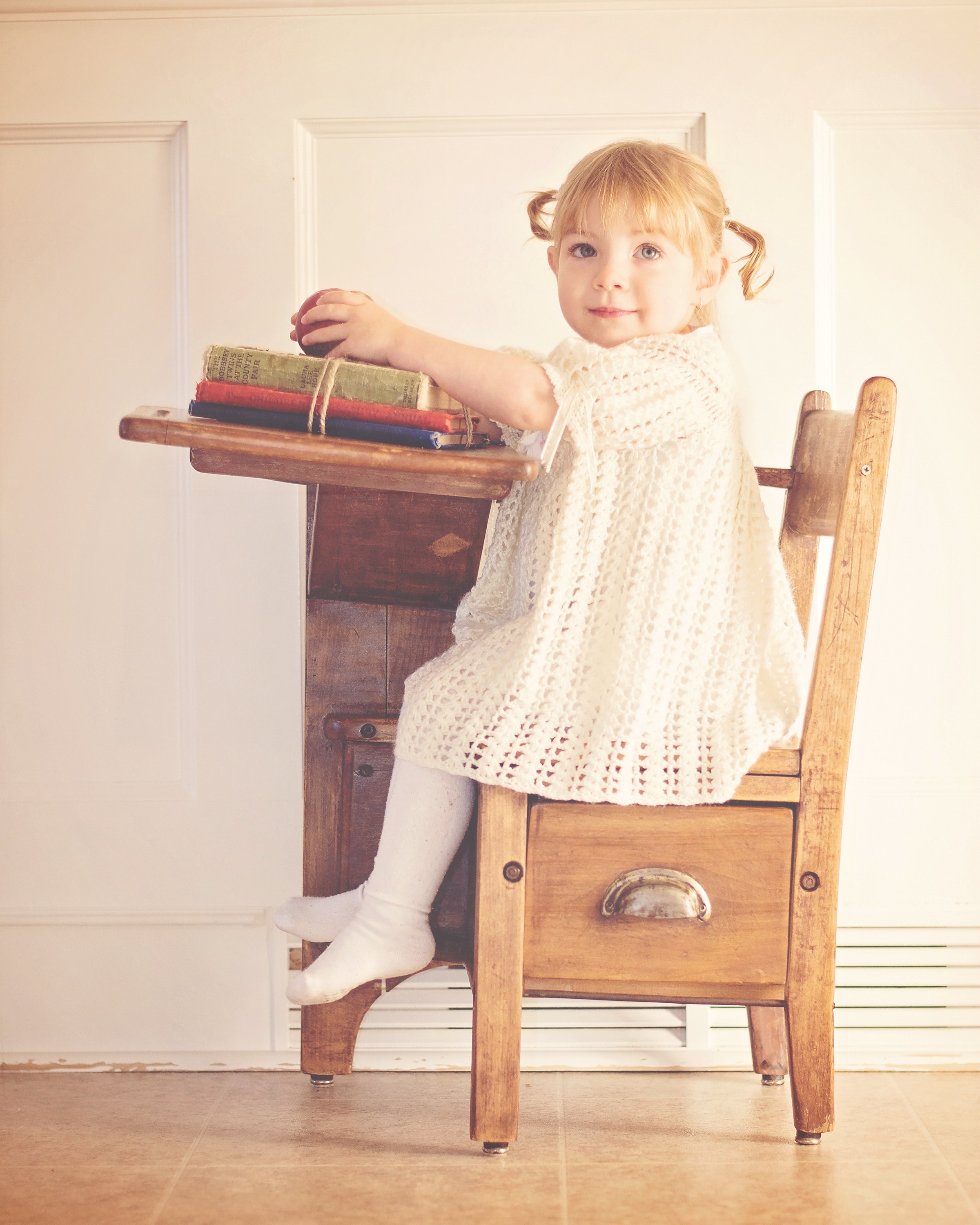 Girl in white dress sitting on brown wooden chair photo