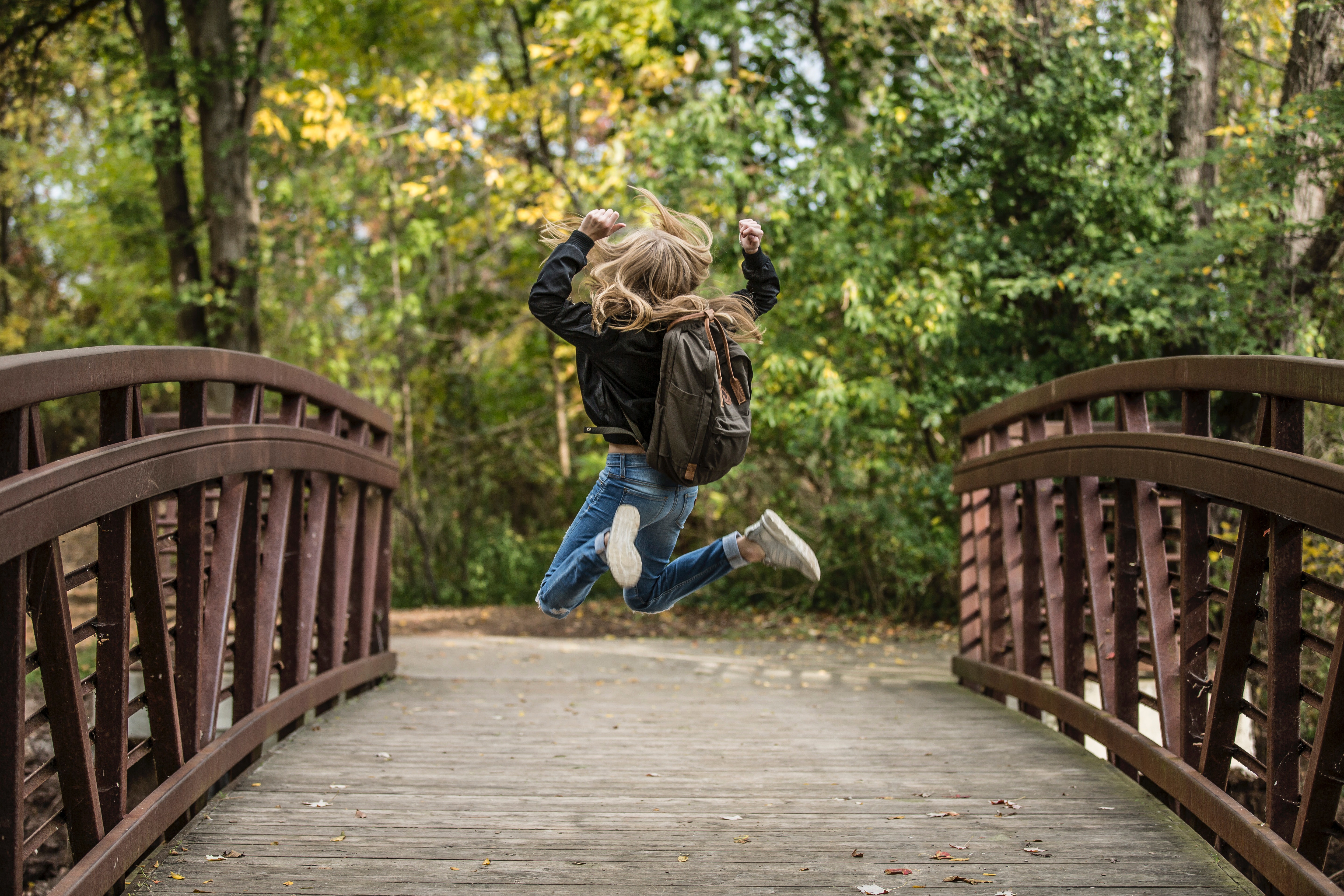 Girl jumping on the bridge wearing black jacket photo