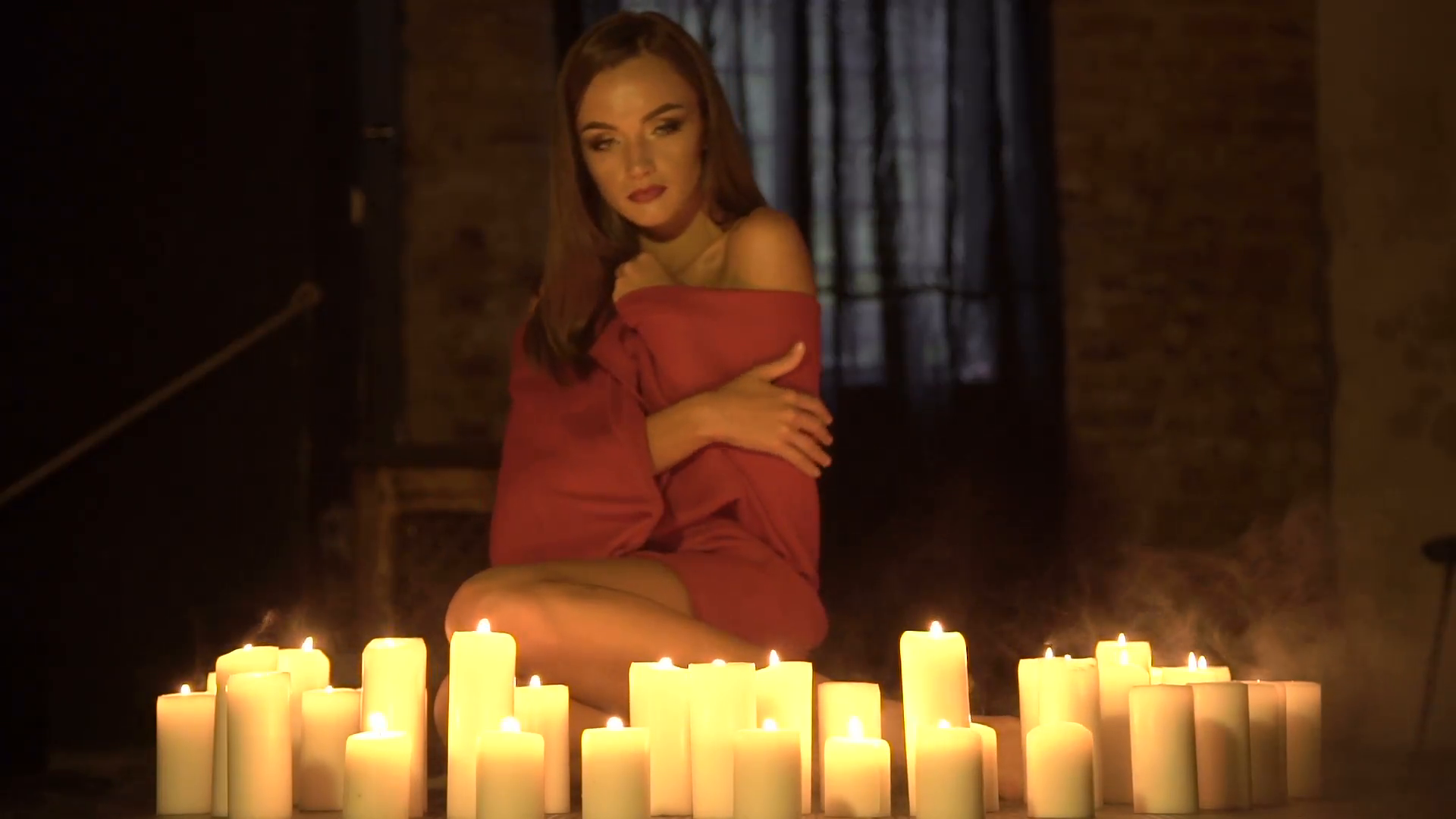 Passionate alone girl sitting on floor near many burning candles in ...