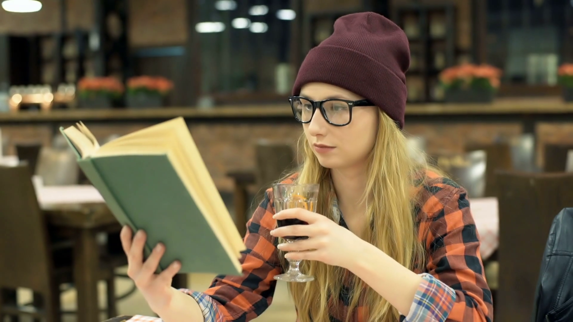 Hipster girl reading book and drinking beverage in the cafe ...