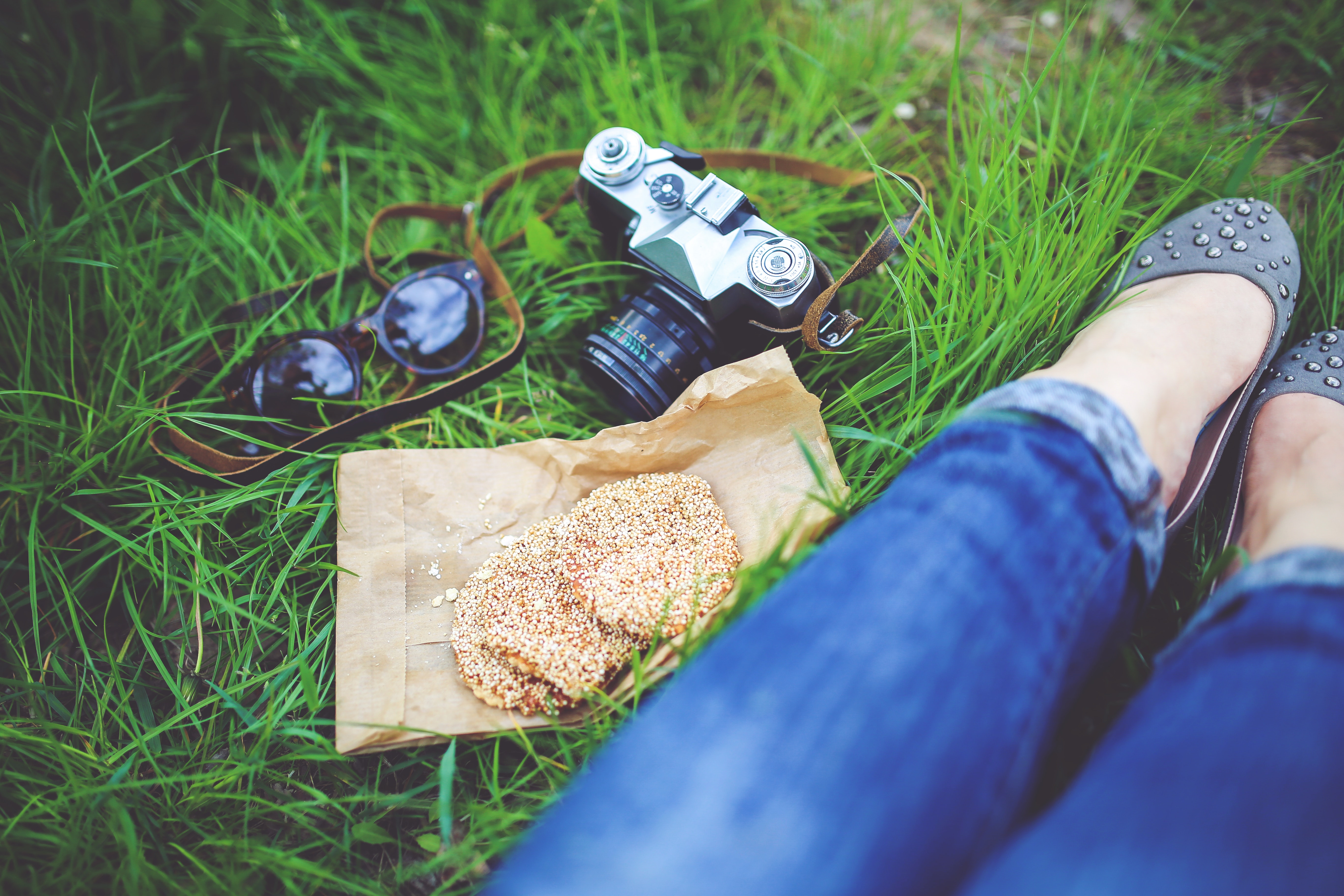Girl resting on green grass with cookies and camera photo