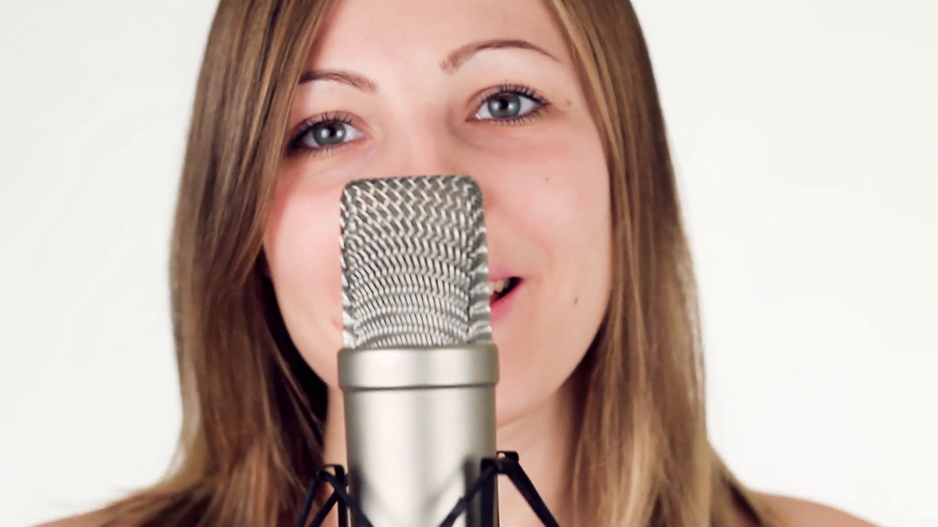 Beautiful girl singing into a studio microphone and looks into the ...