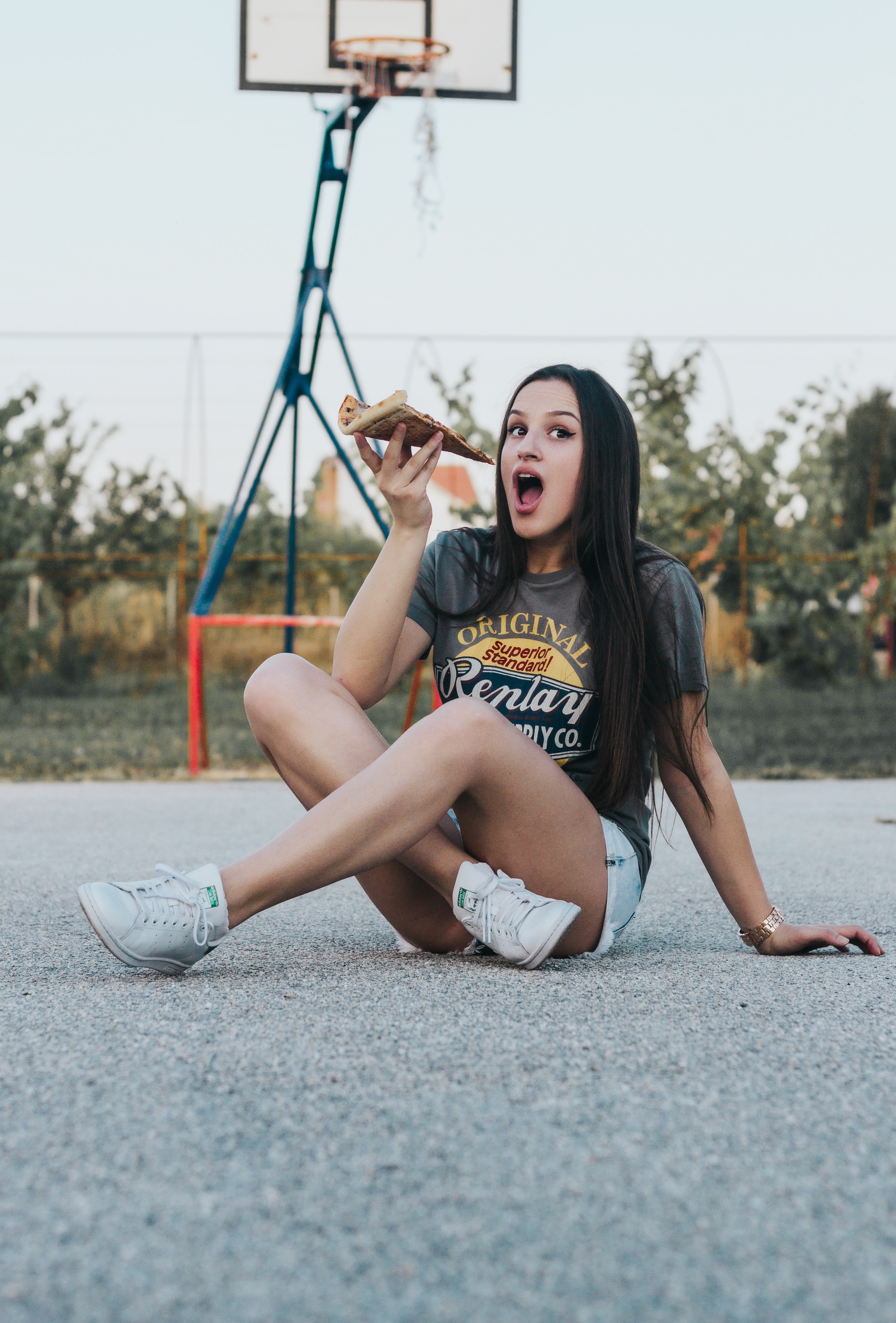 Girl sitting on basketball field holding pizza photo