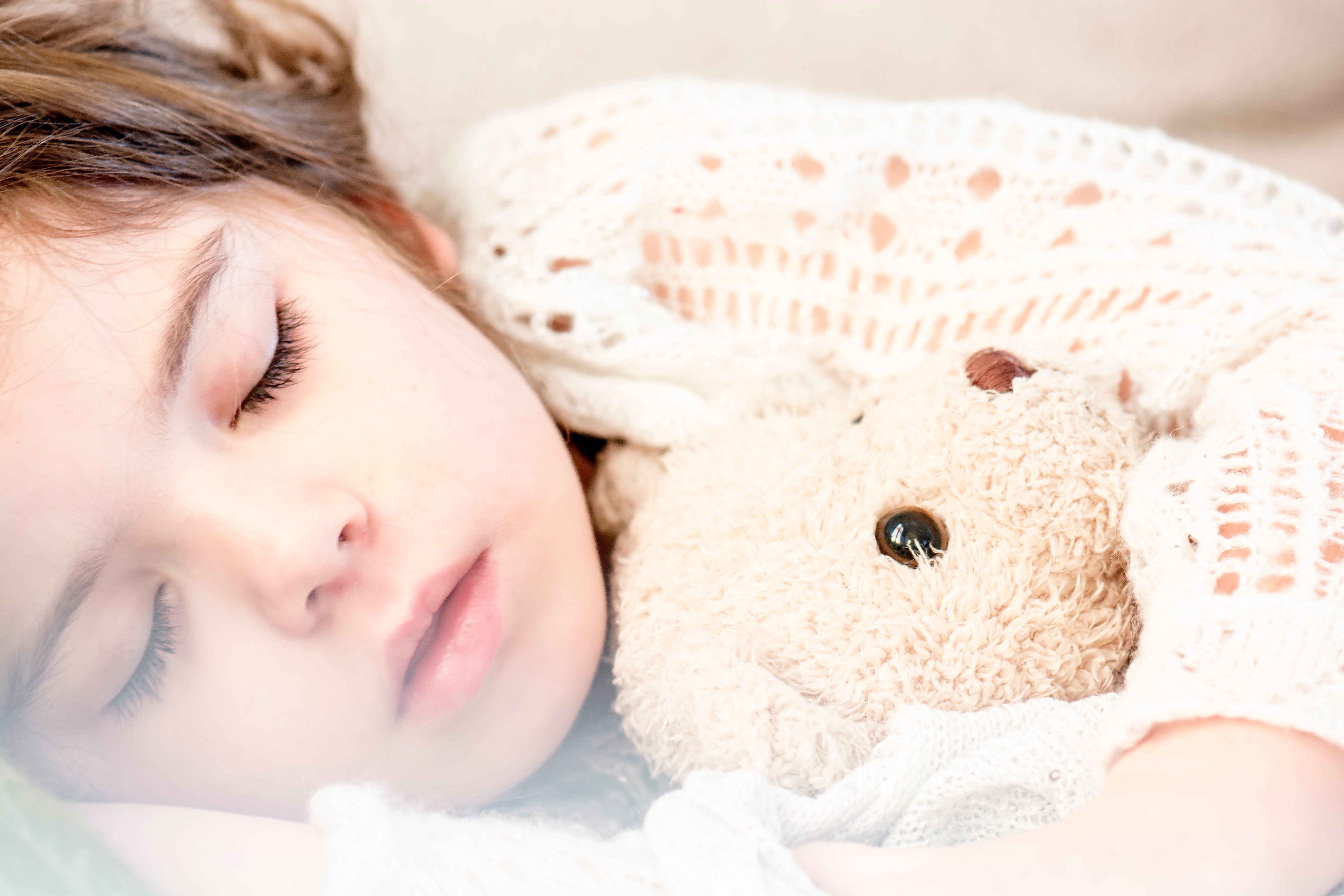 Girl sleeping with her brown plush toy photo