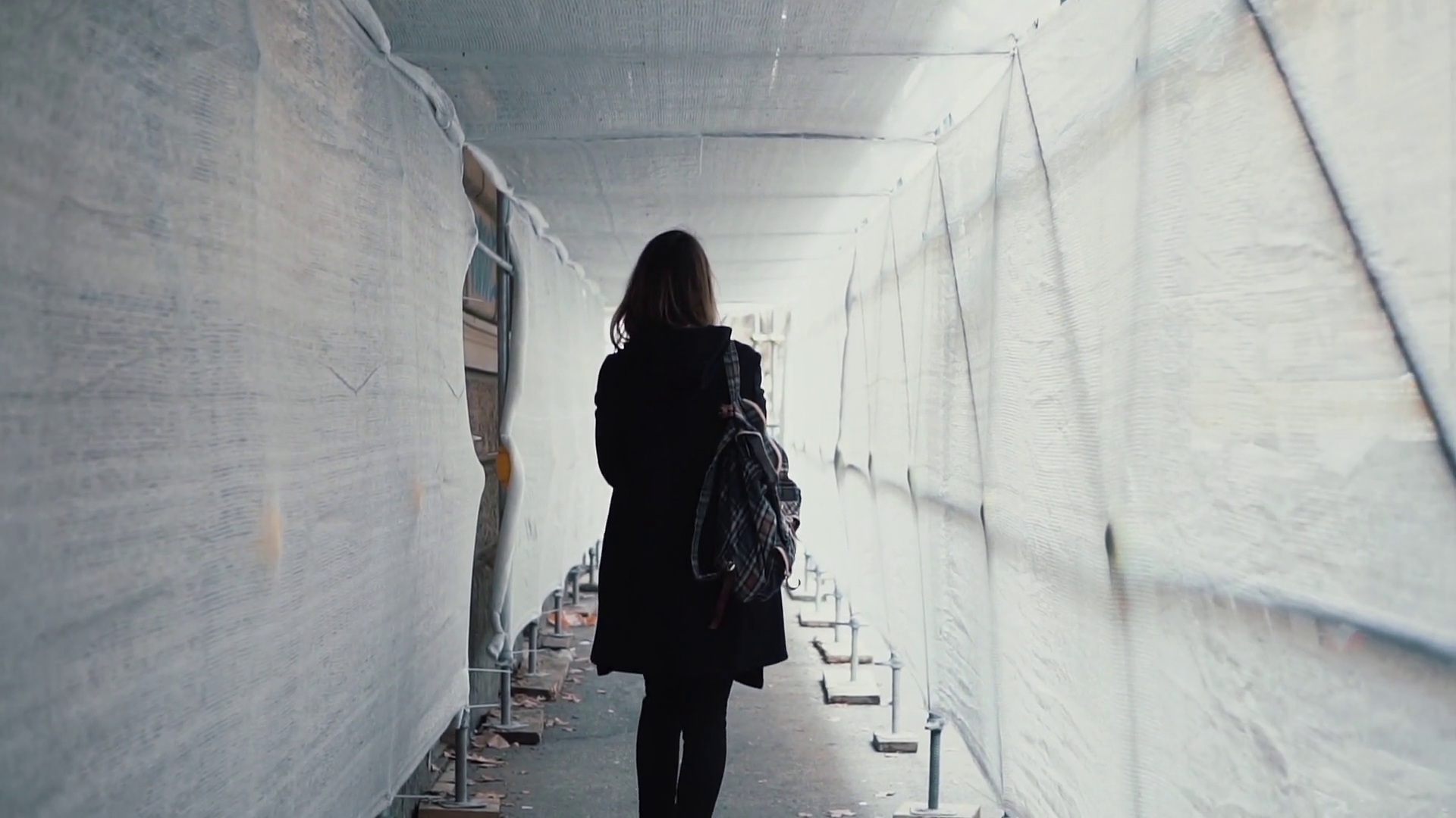 Student girl walking through the white construction corridor. Back ...