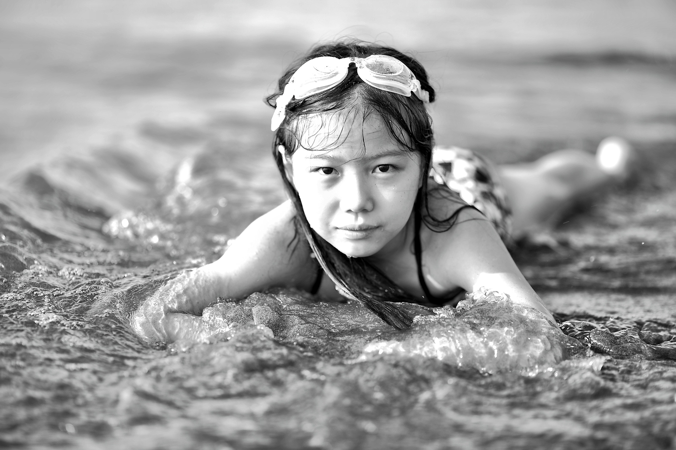 Girl wearing goggles on beach in black and white photo