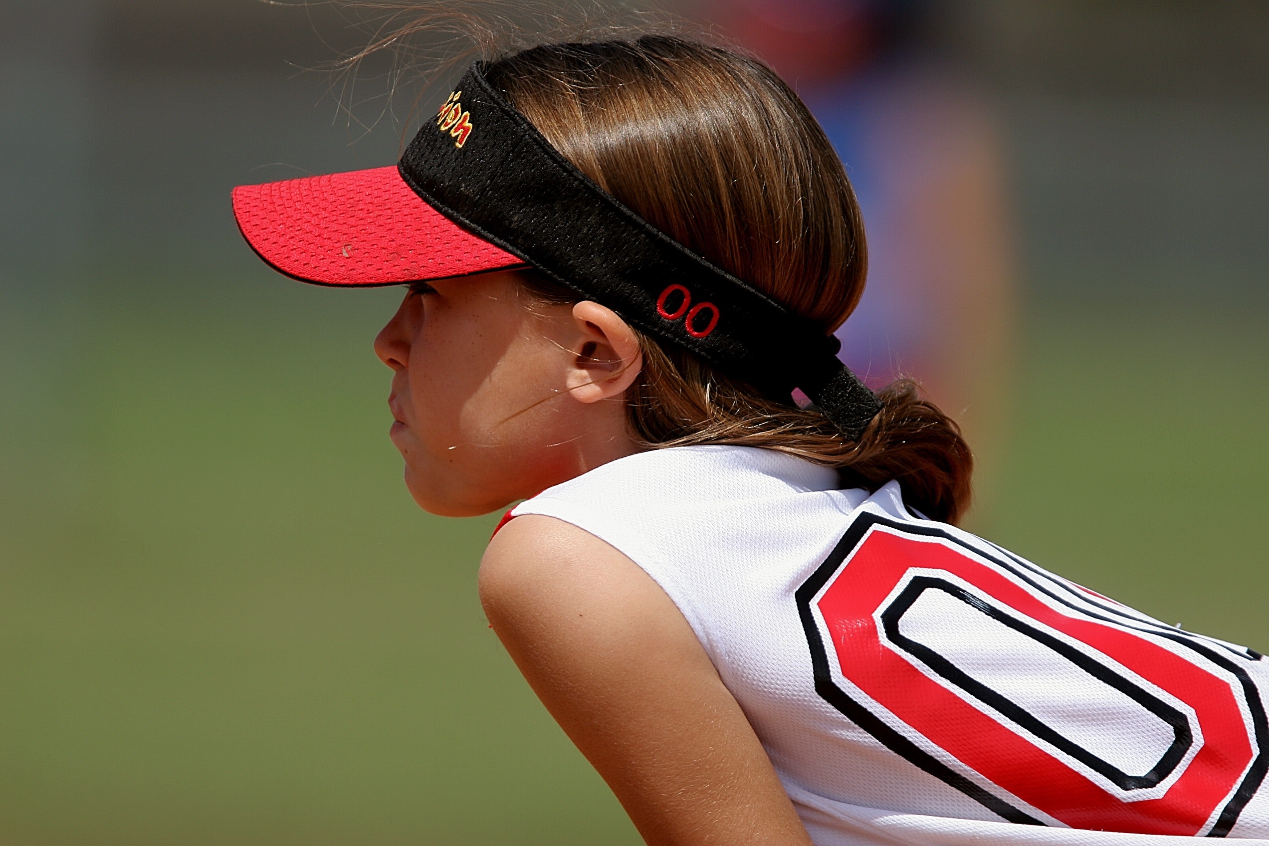 Girl wearing red and black sun visor and white and red jersey top photo