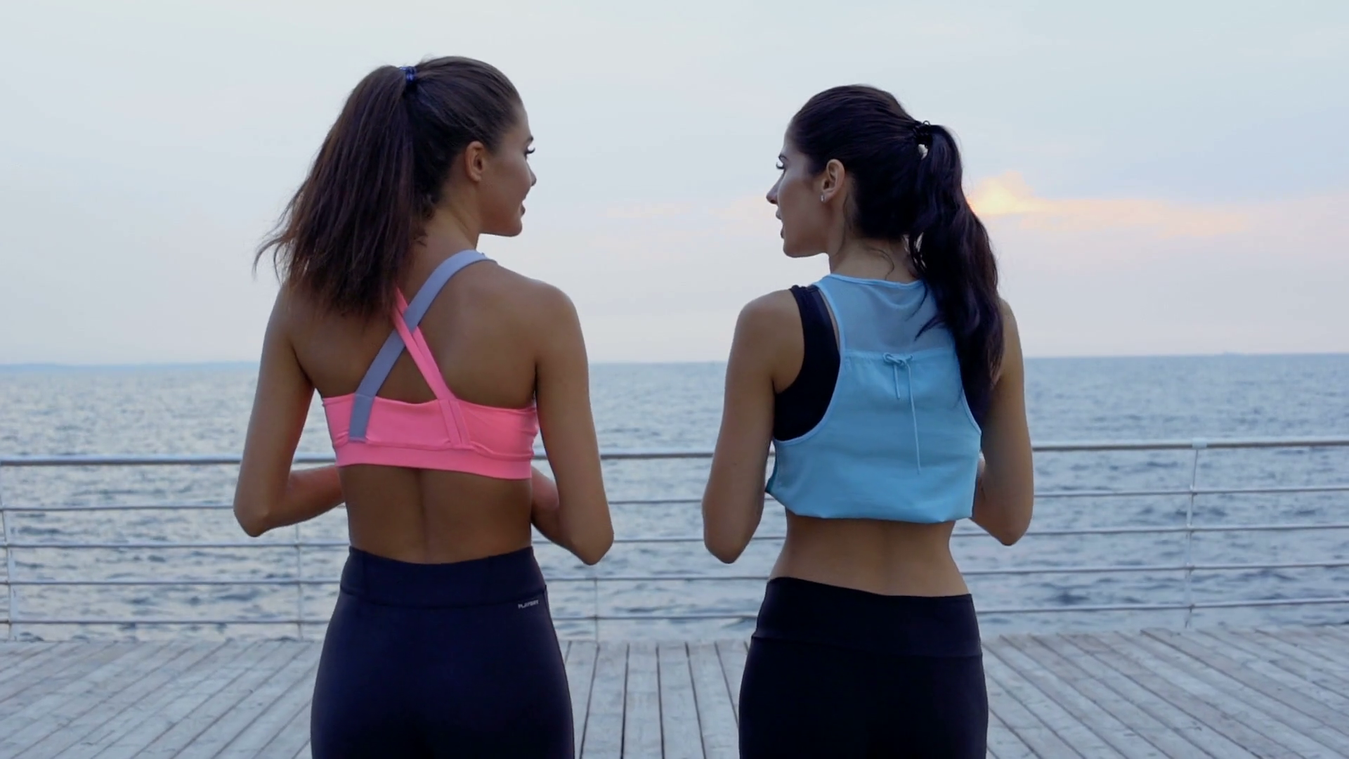 Back view of young smiling fitness girls talking and walking at the ...